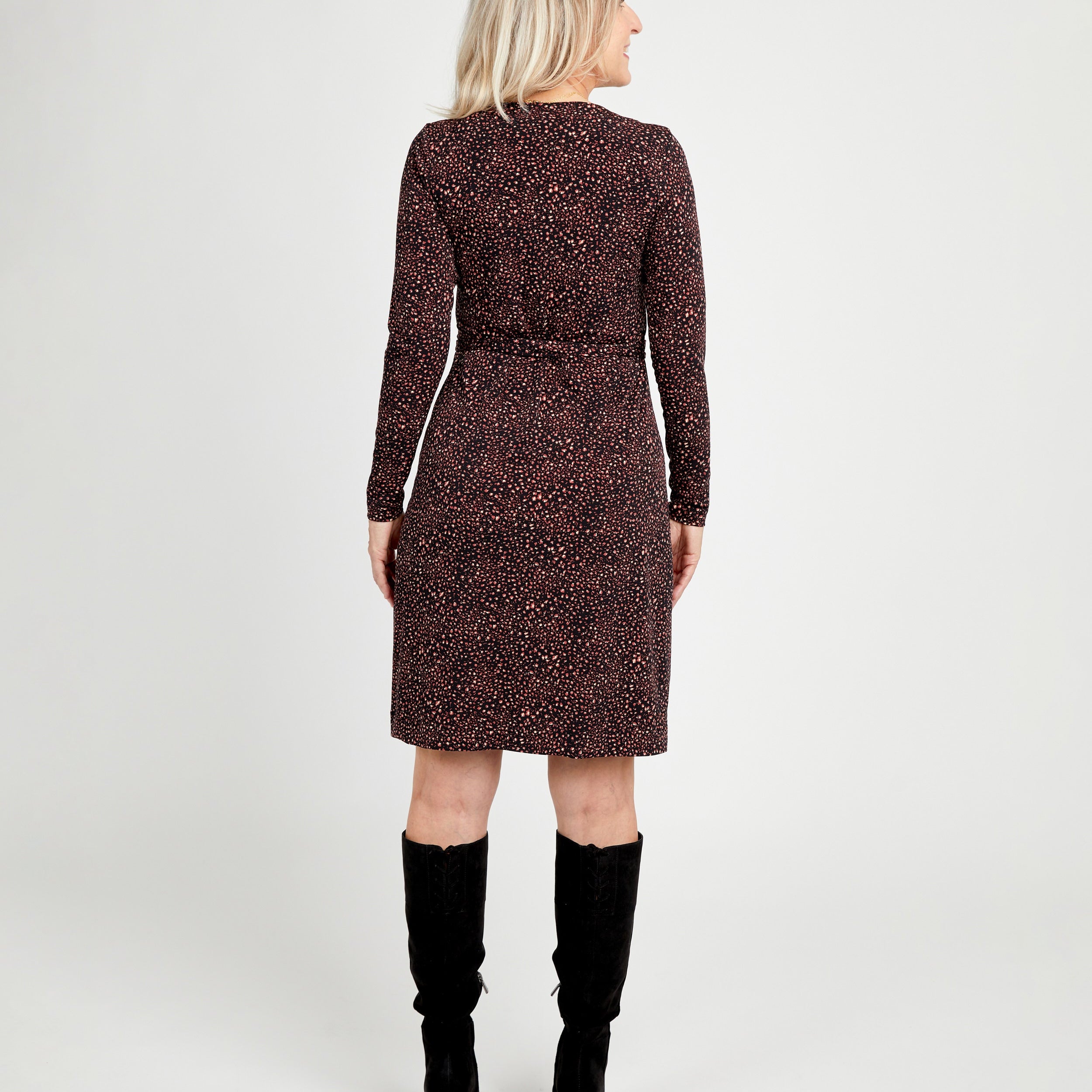 Woman wearing a patterned dress with long sleeves and a belt, standing against a white background.This dress is the Appleton Wrap Dress sewing pattern from Cashmerette.