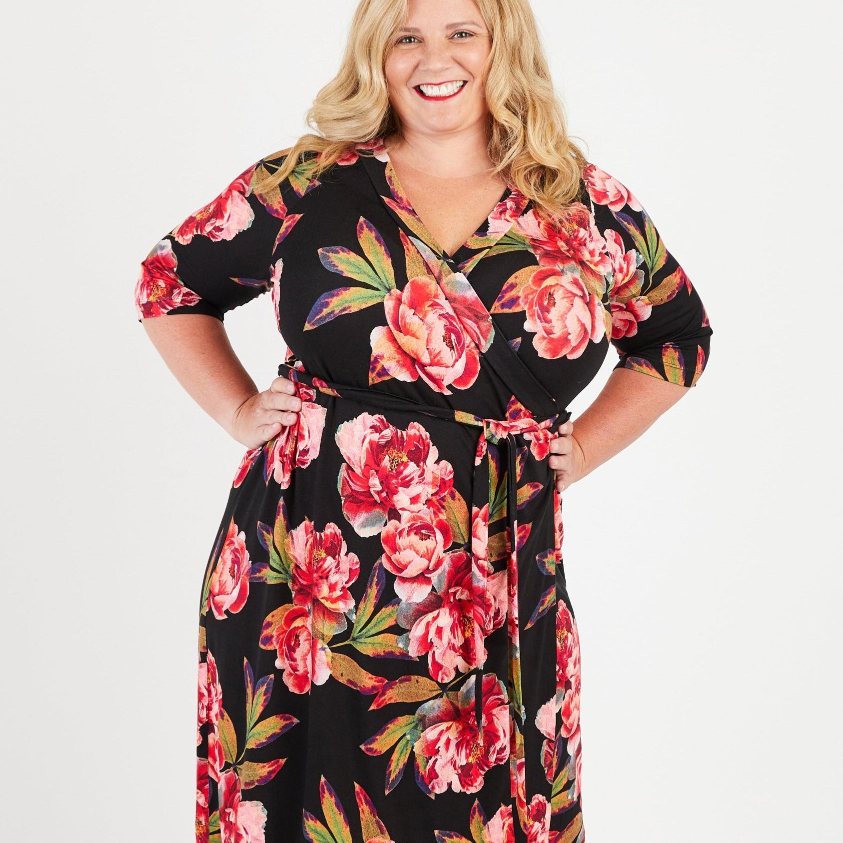 Woman wearing a floral dress on a white background. This dress is the Appleton Wrap Dress sewing pattern from Cashmerette.