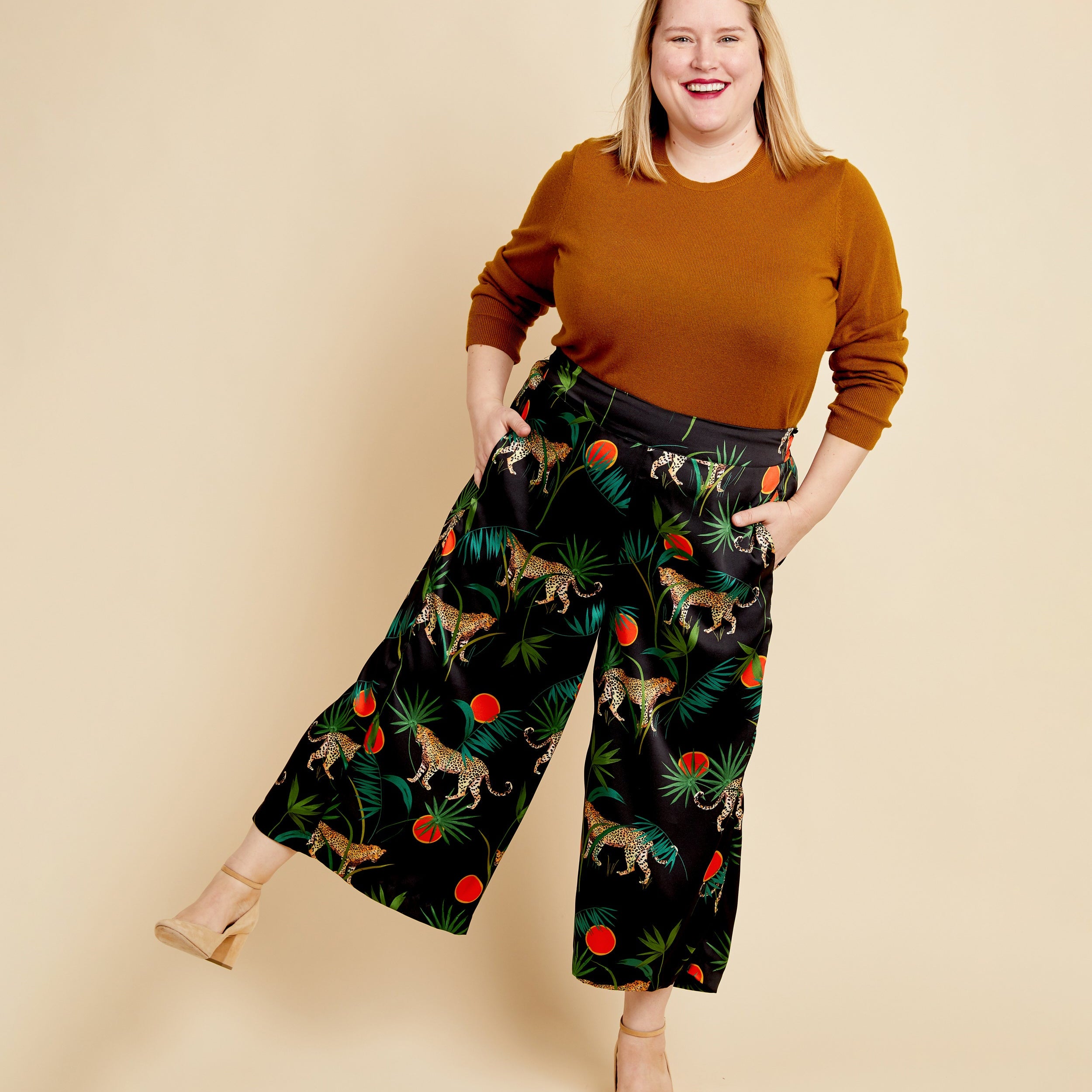 Woman wearing a brown sweater and patterned pants on a beige background. These pants are the Calder Pants & Shorts sewing pattern from Cashmerette.