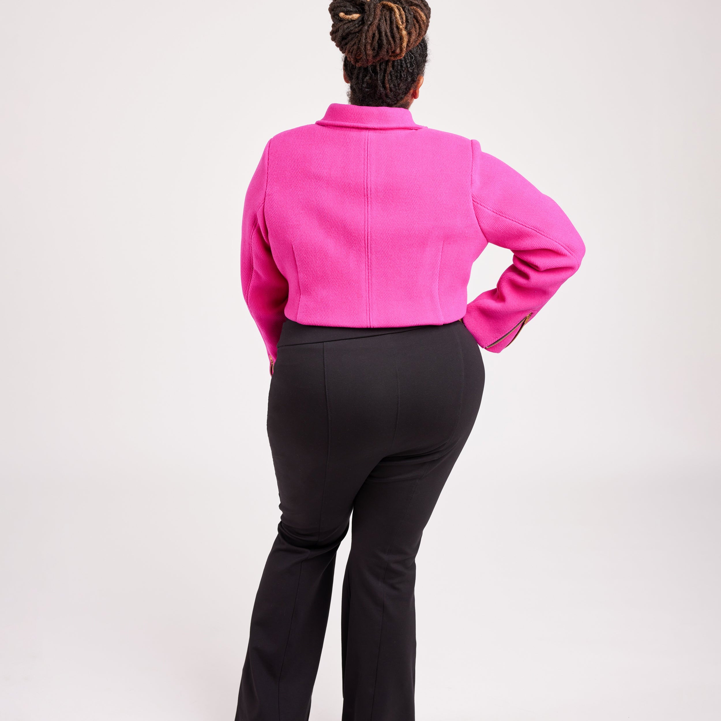 Person wearing a bright pink jacket and black pants on a white background. This biker jacket is the Canton Moto Jacket sewing pattern from Cashmerette.