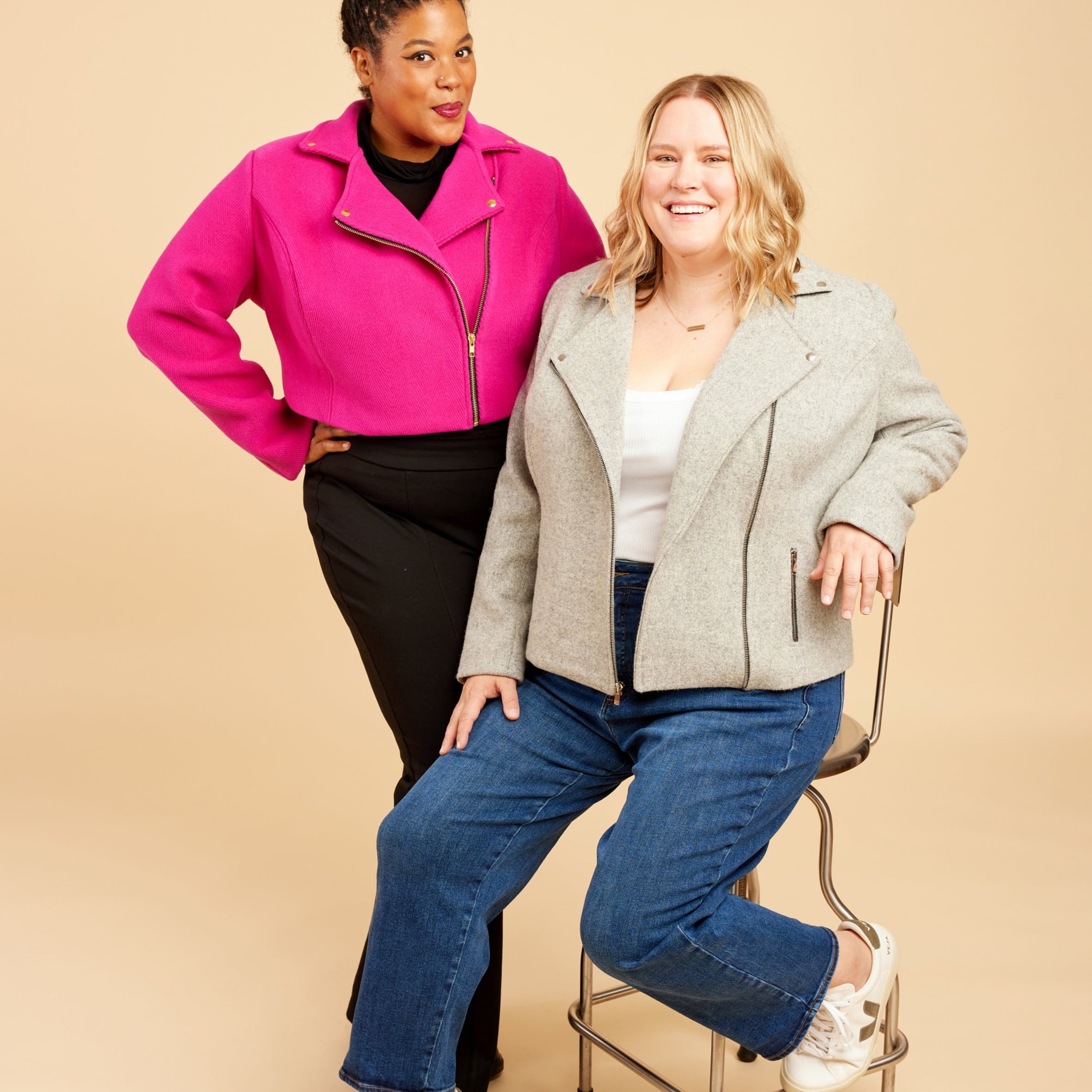 Two women posing together against a beige background. This biker jacket is the Canton Moto Jacket sewing pattern from Cashmerette.