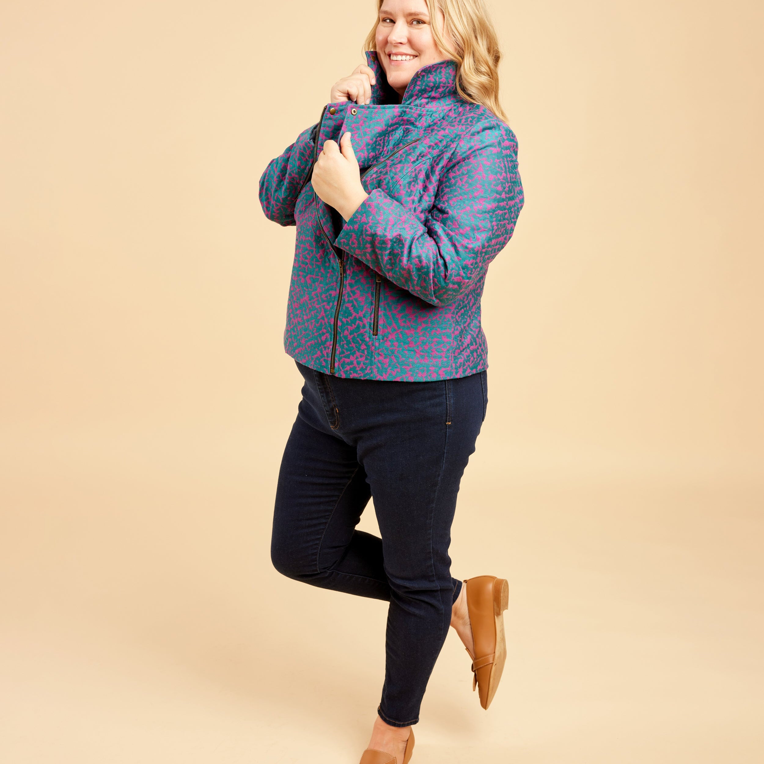 Woman wearing a patterned jacket on a beige background. This biker jacket is the Canton Moto Jacket sewing pattern from Cashmerette.