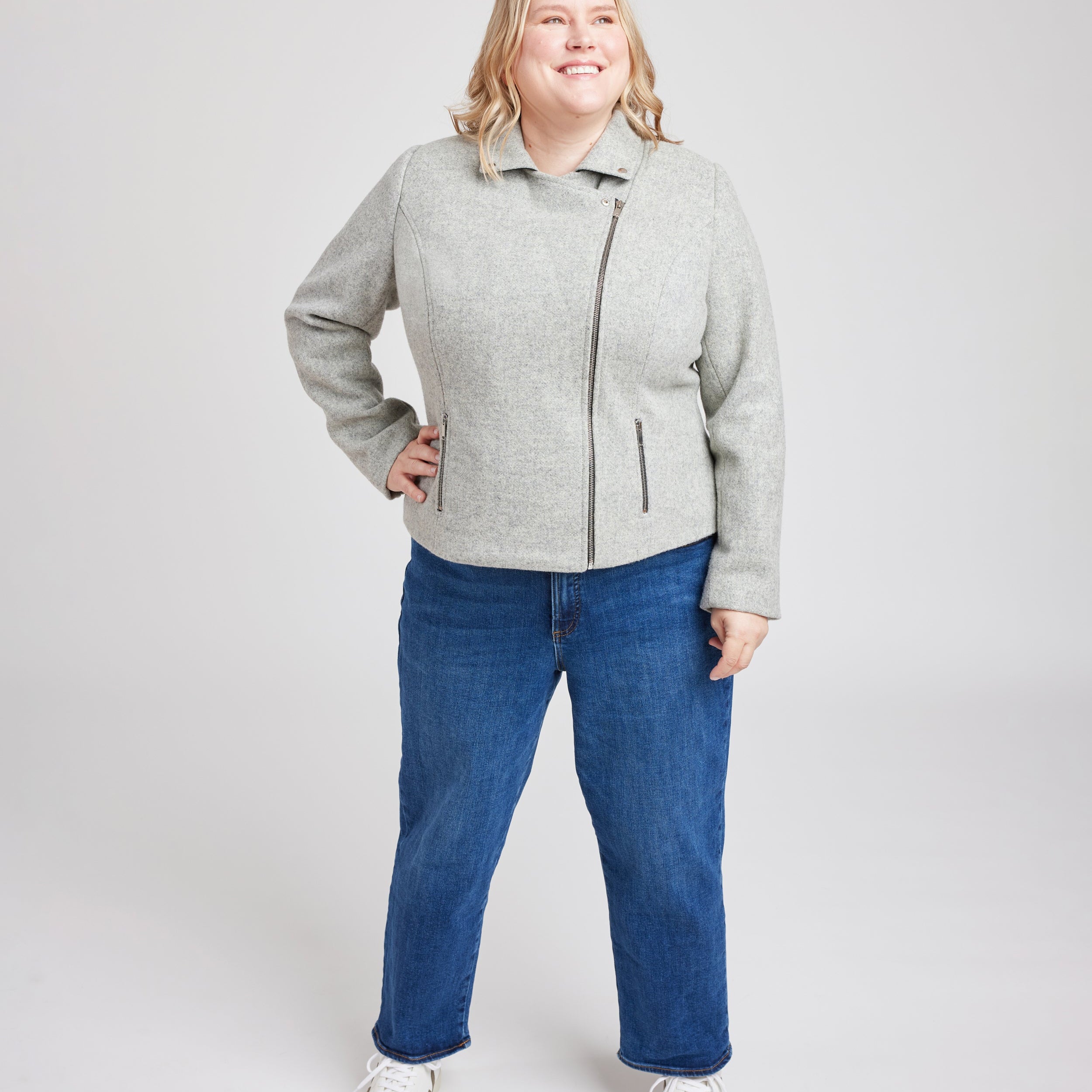Person wearing a gray jacket and blue jeans on a white background. This biker jacket is the Canton Moto Jacket sewing pattern from Cashmerette.