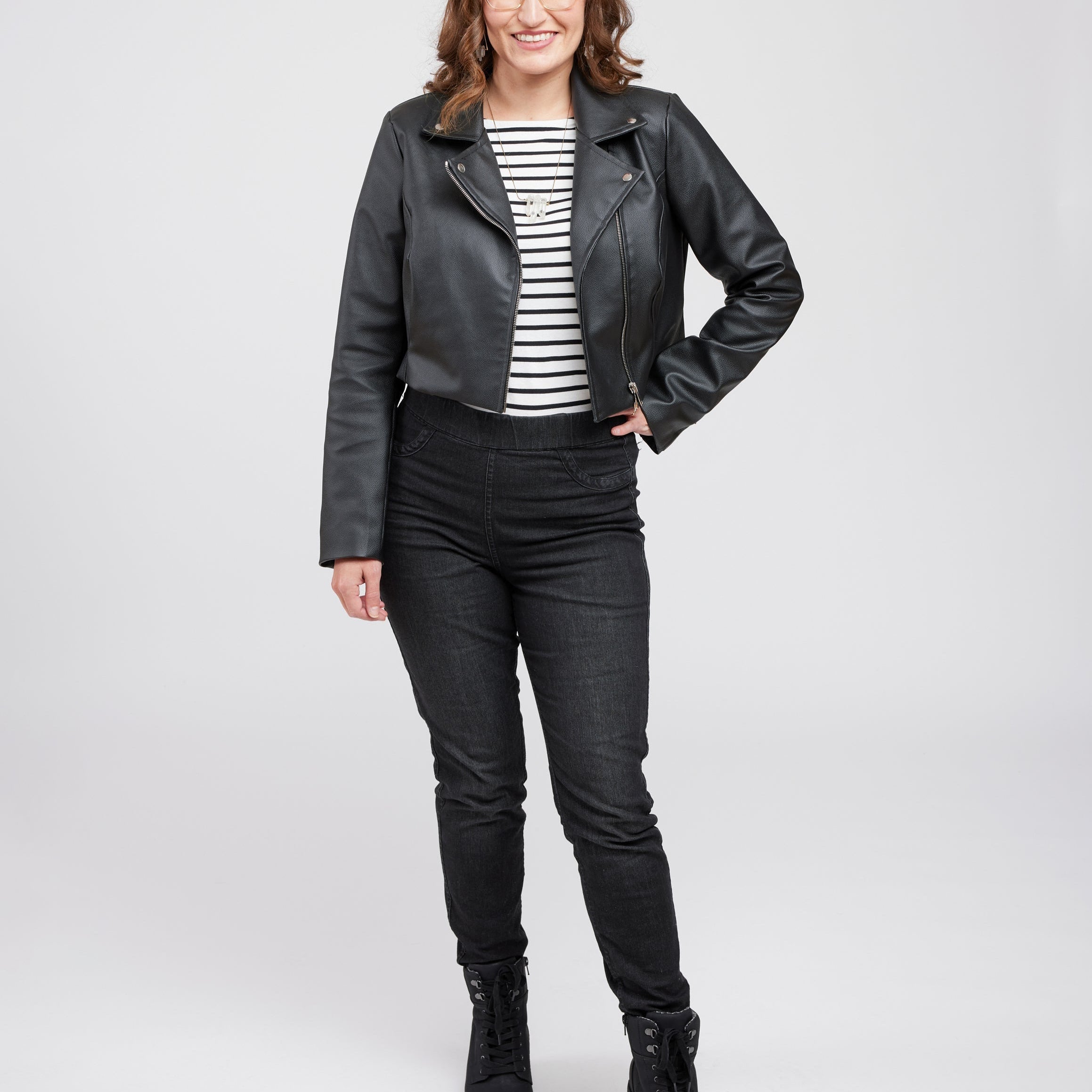 Woman wearing a black leather jacket in front of a white wall. This biker jacket is the Canton Moto Jacket sewing pattern from Cashmerette.
