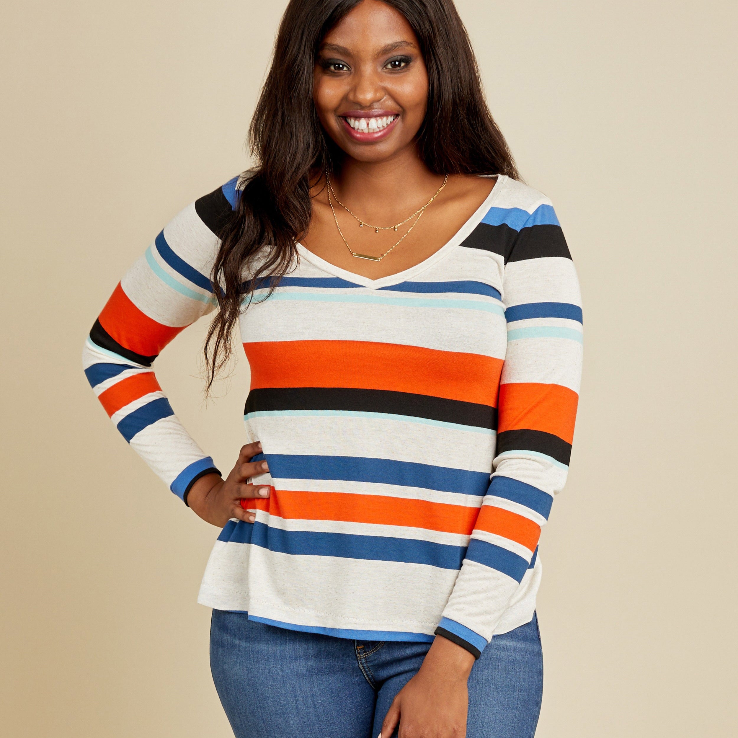 Woman wearing a colorful striped sweater against a beige background. This t-shirt is the Concord T-Shirt sewing pattern from Cashmerette.