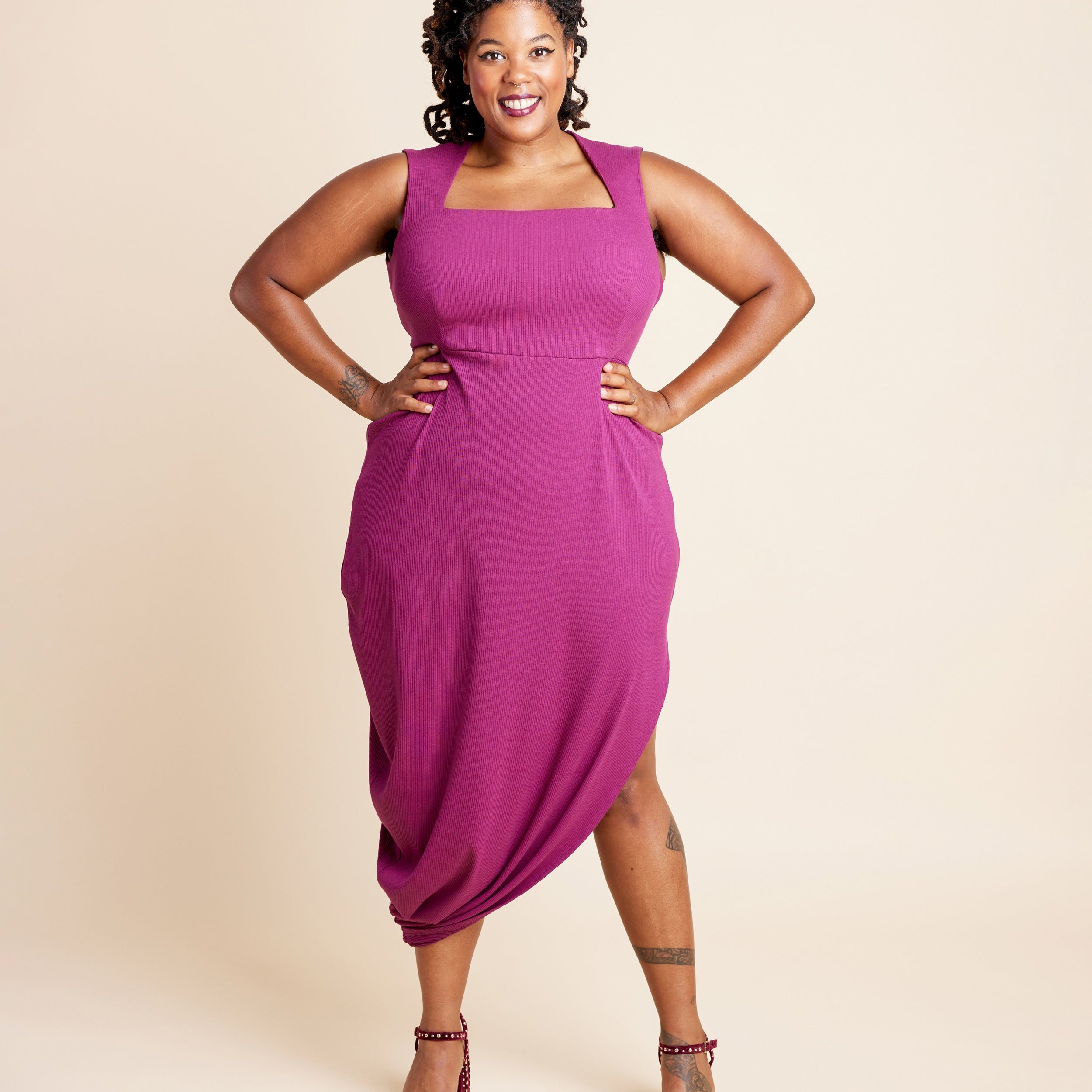 Woman wearing a magenta dress against a beige background. This is the Grafton Dress, Top & Skirt sewing pattern from Cashmerette.