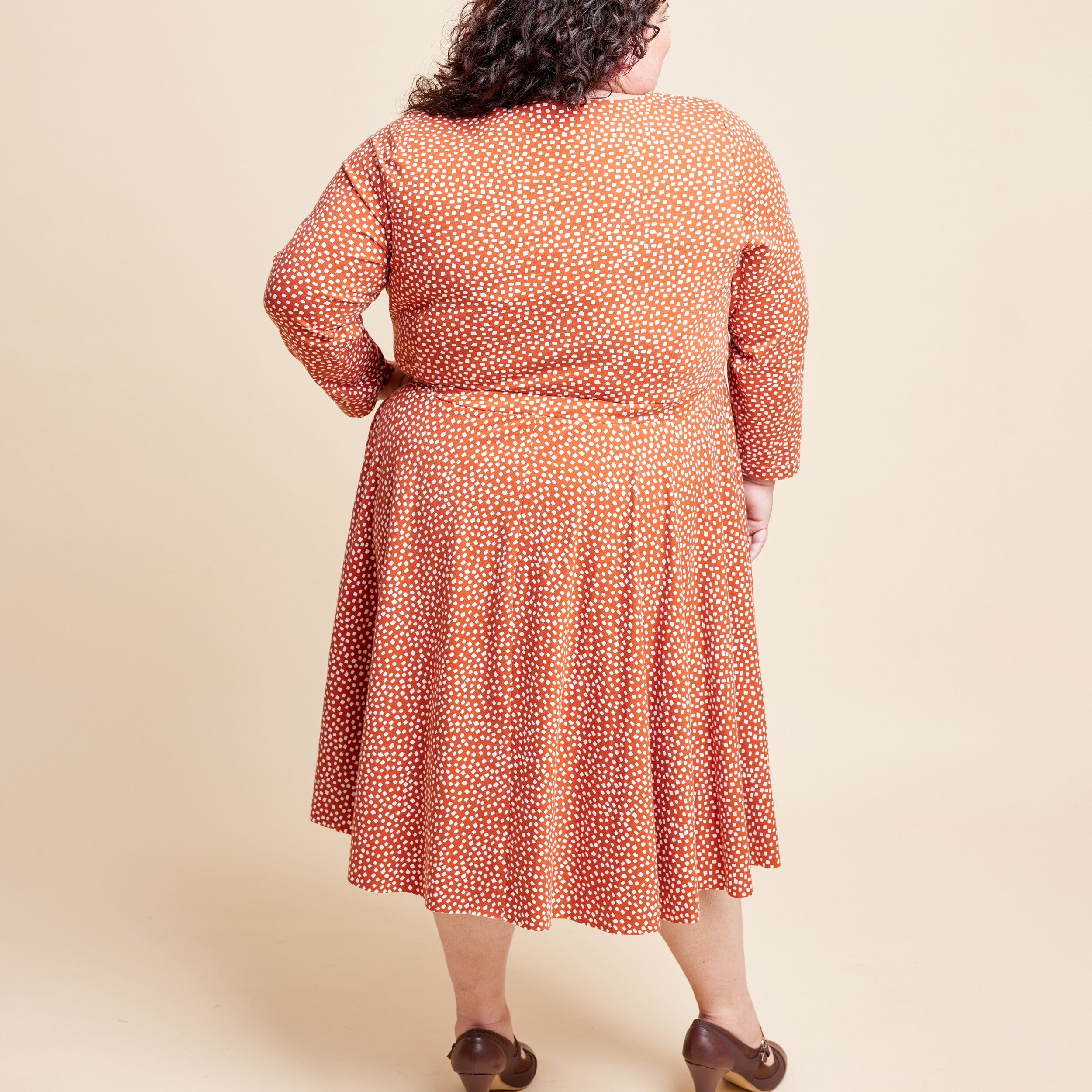 Woman wearing a patterned dress on a beige background. This is the Grafton Dress, Top & Skirt sewing pattern from Cashmerette.
