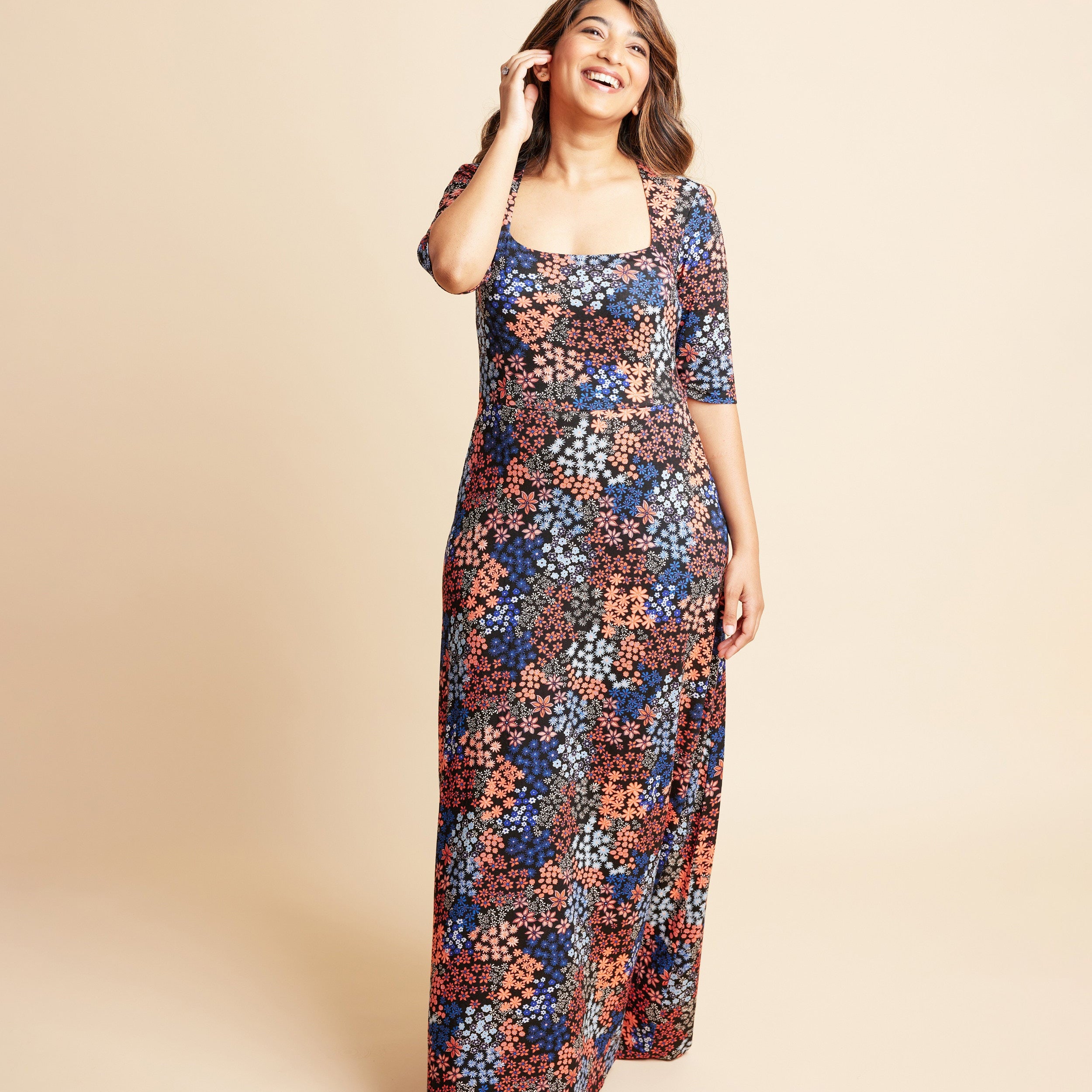 Woman wearing a floral dress on a beige background. This is the Grafton Dress, Top & Skirt sewing pattern from Cashmrette.