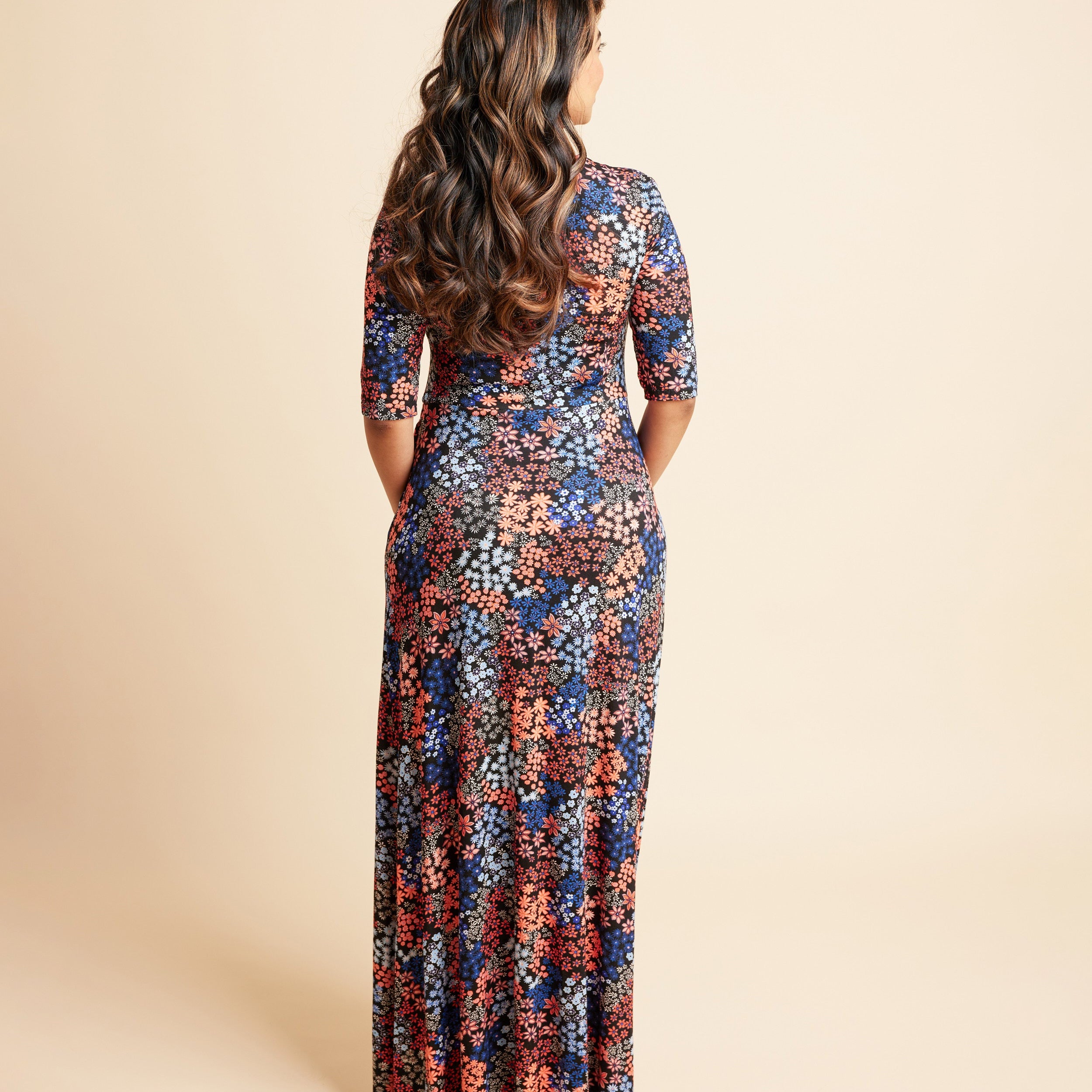 Woman wearing a floral dress on a beige background. This is the Grafton Dress, Top & Skirt sewing pattern from Cashmrette.