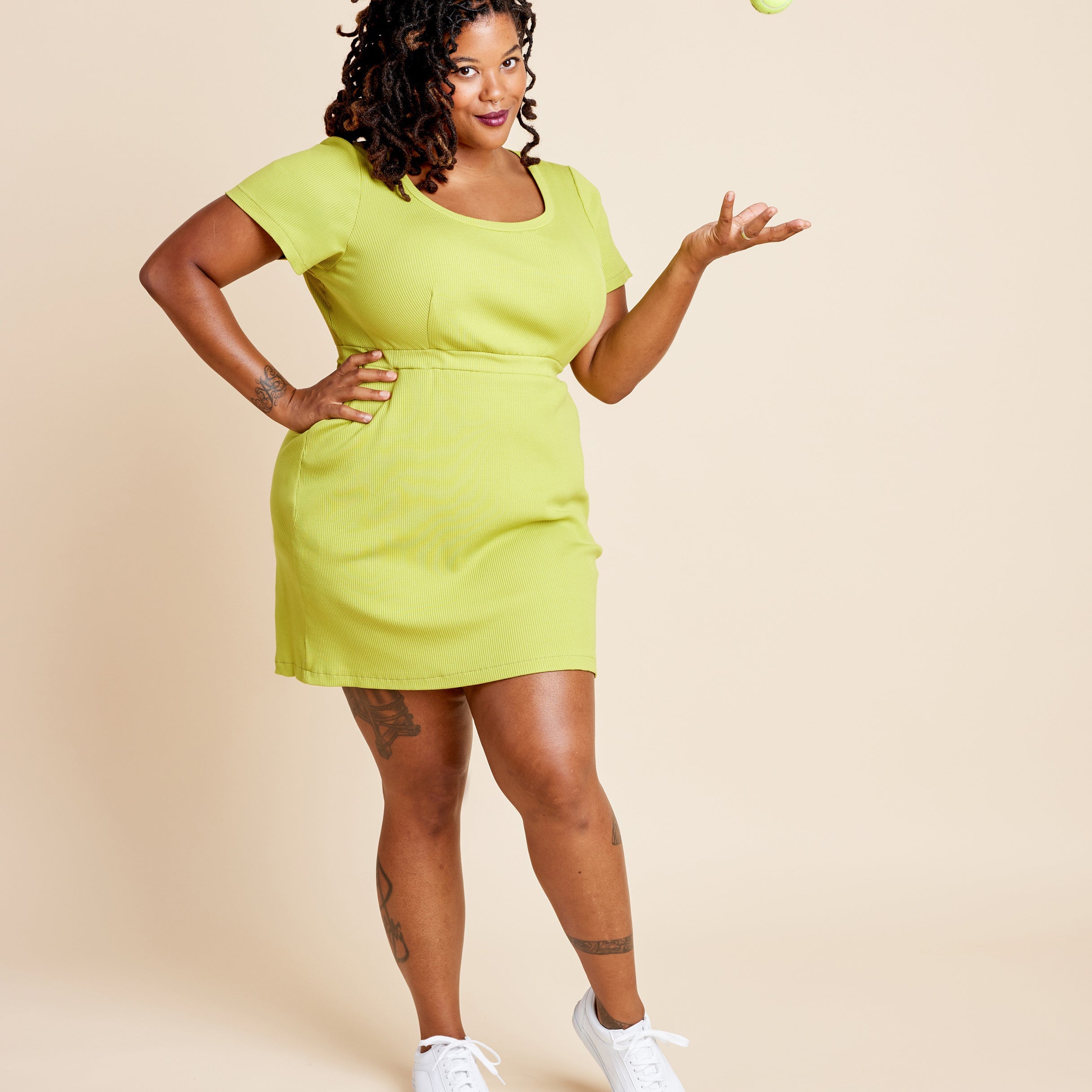Woman wearing a bright green dress against a beige background. This is the Grafton Dress, Top & Skirt sewing pattern from Cashmerette.