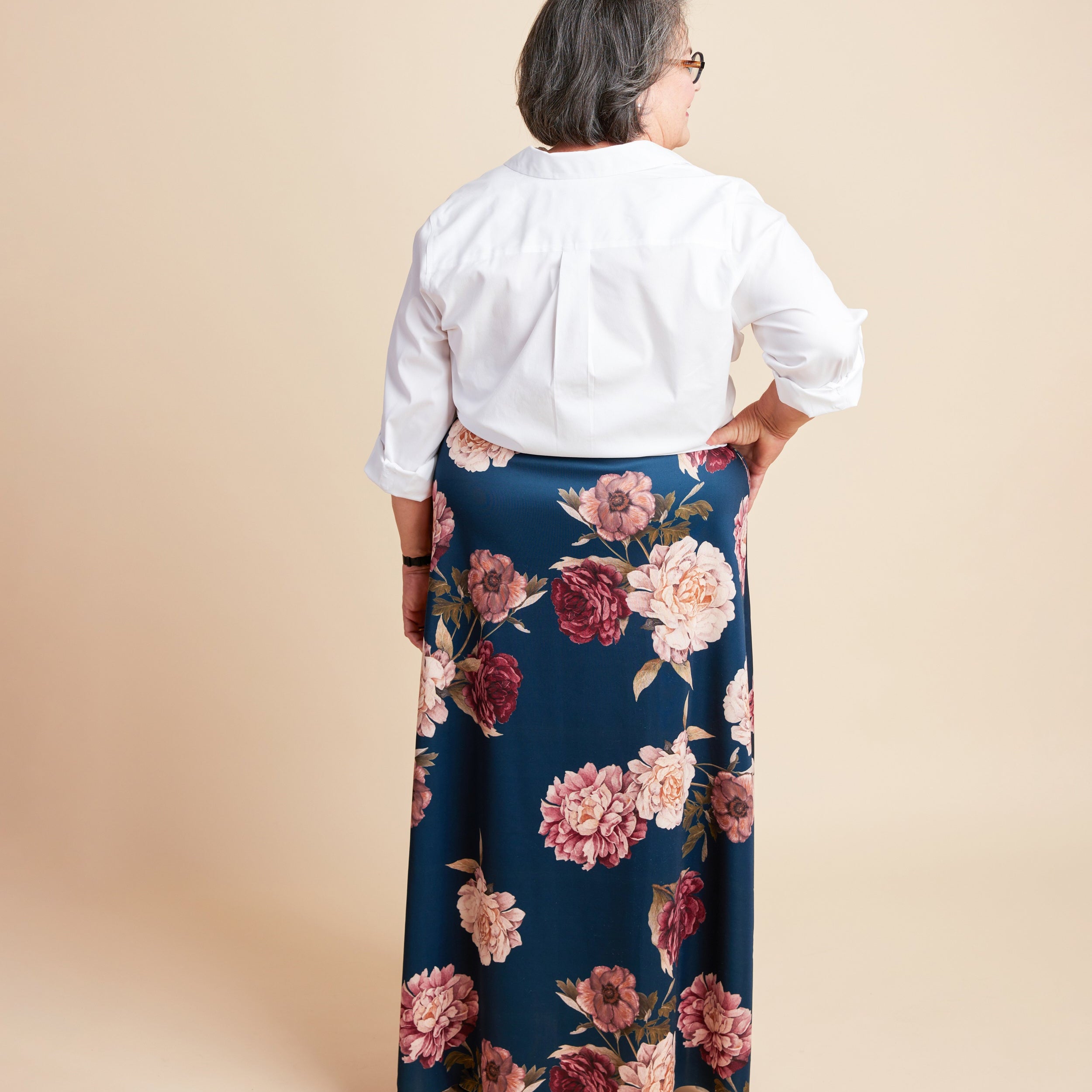 Person wearing a white blouse and floral skirt on a beige background. This is the Grafton Dress, Top & Skirt sewing pattern from Cashmerette.
