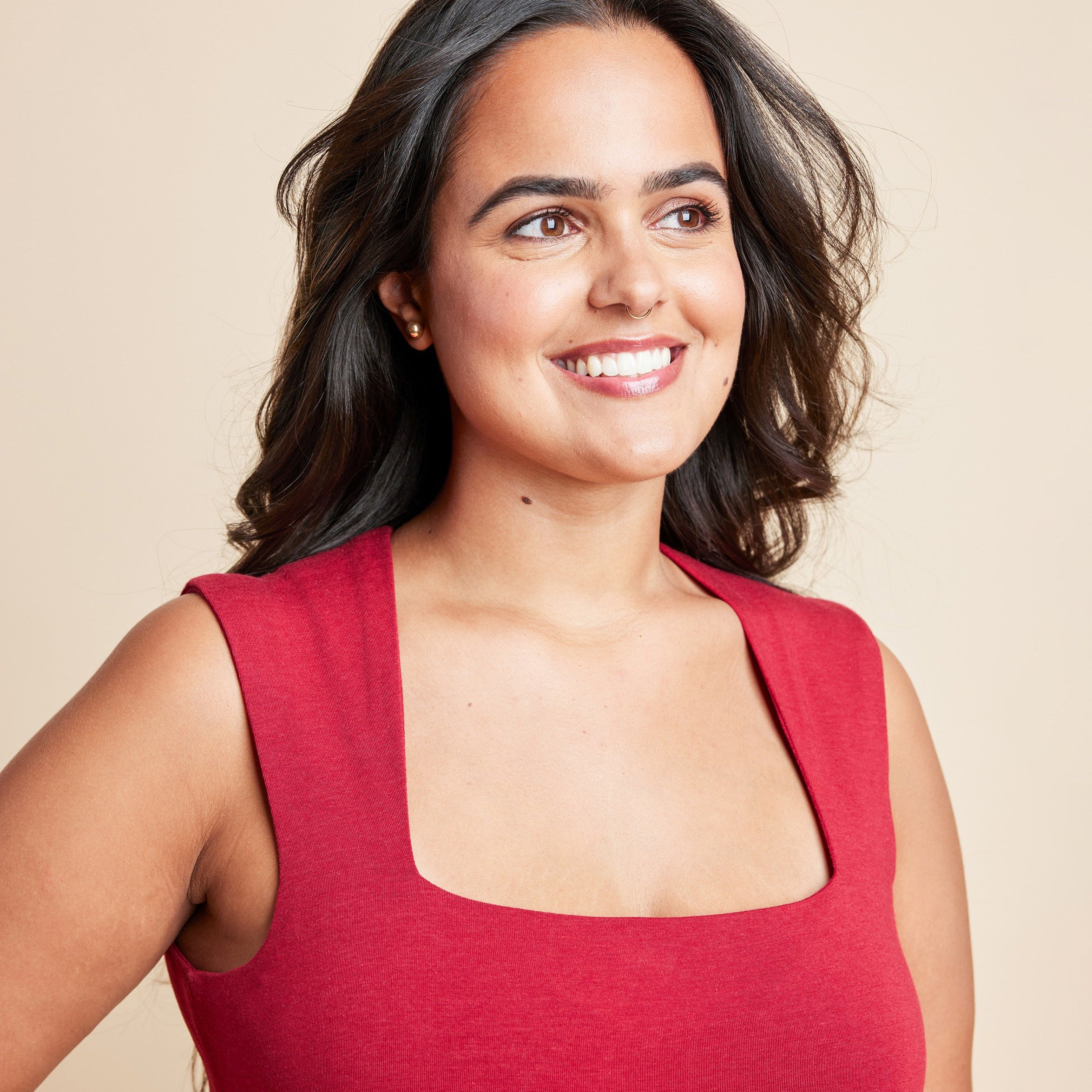 Woman wearing a red sleeveless top against a beige background. This is the Grafton Dress, Top & Skirt sewing pattern from Cashmrette.