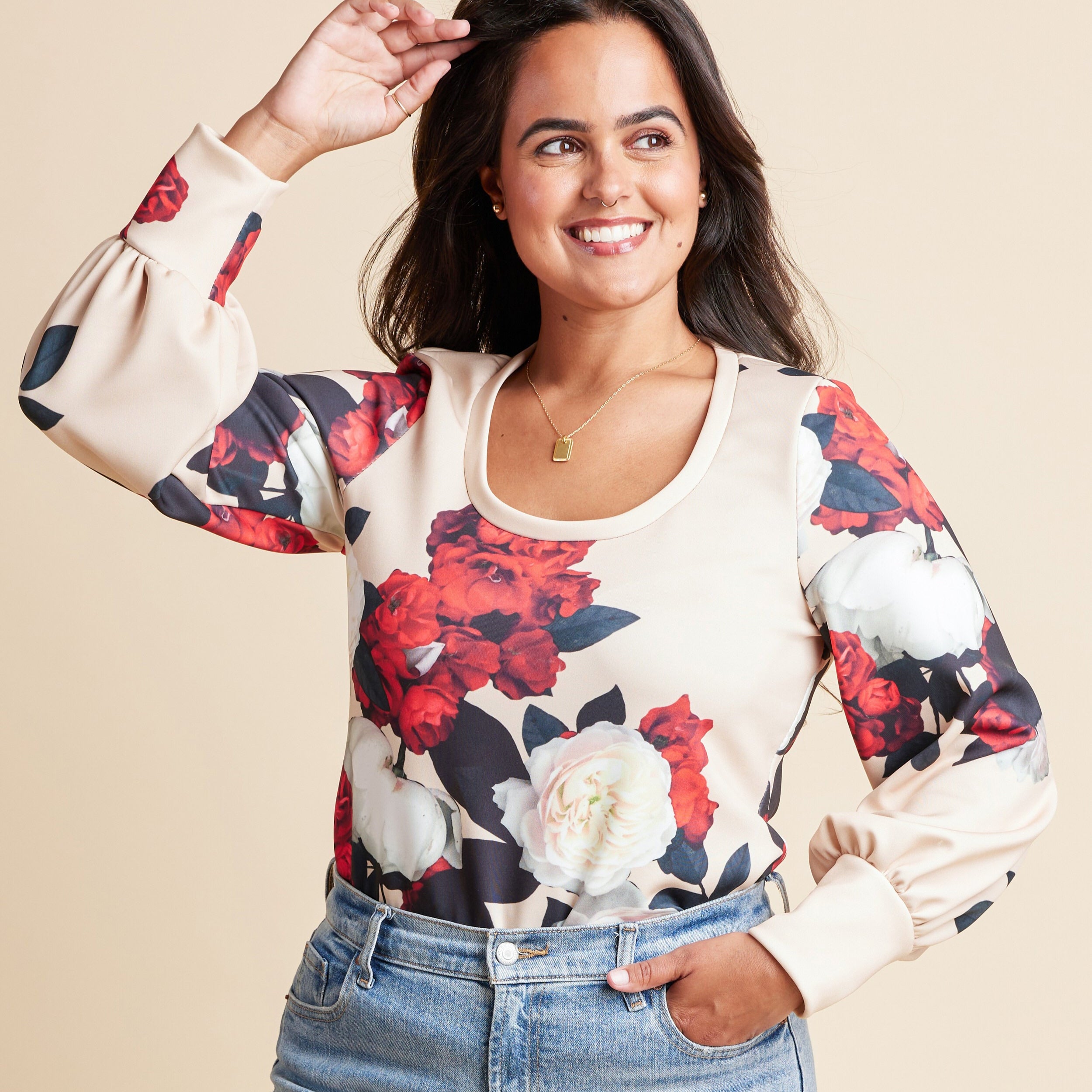 Woman wearing a floral blouse with a beige background. This is the Grafton Dress, Top & Skirt sewing pattern from Cashmrette.
