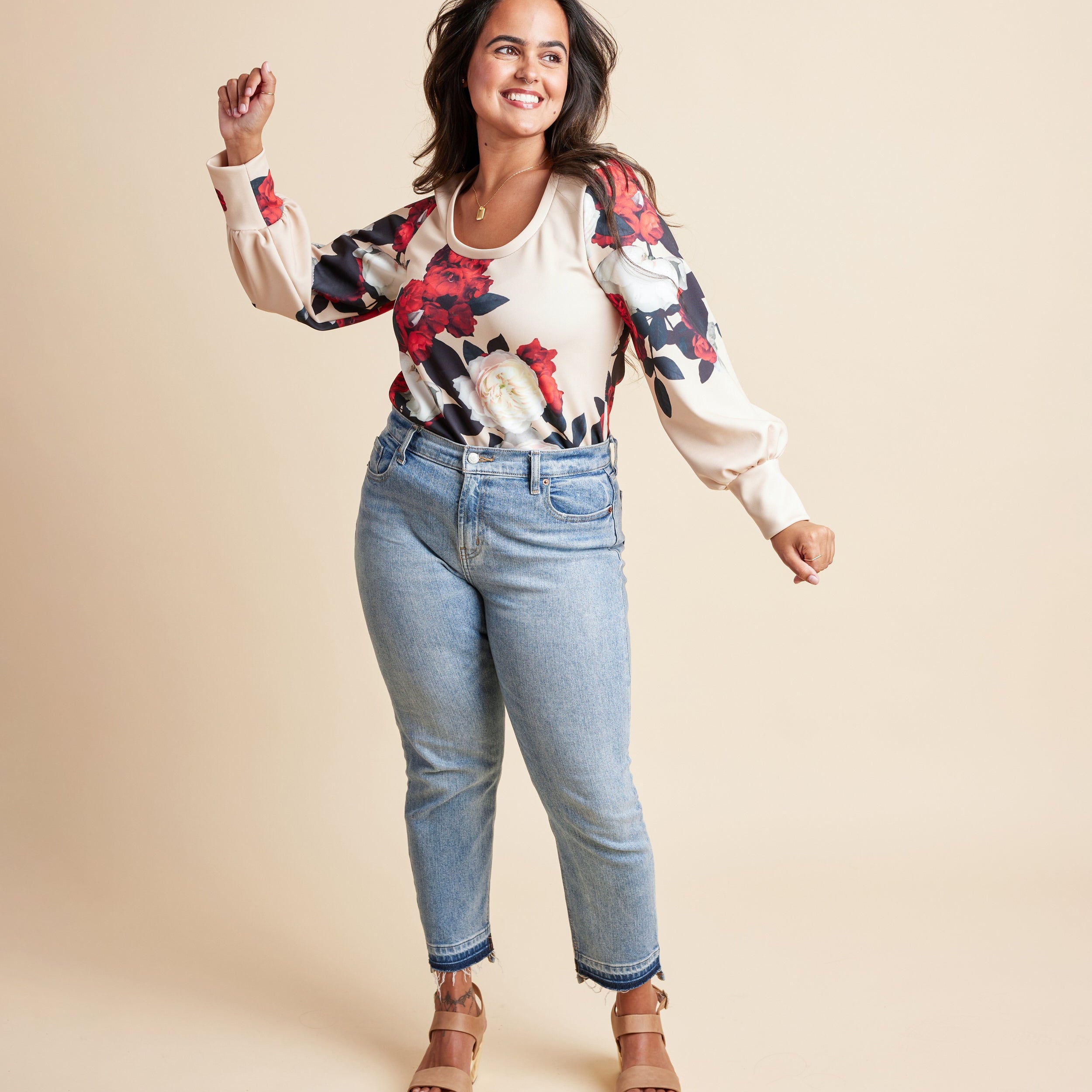 Woman wearing a floral blouse and jeans on a beige background. This is the Grafton Dress, Top & Skirt sewing pattern from Cashmrette.