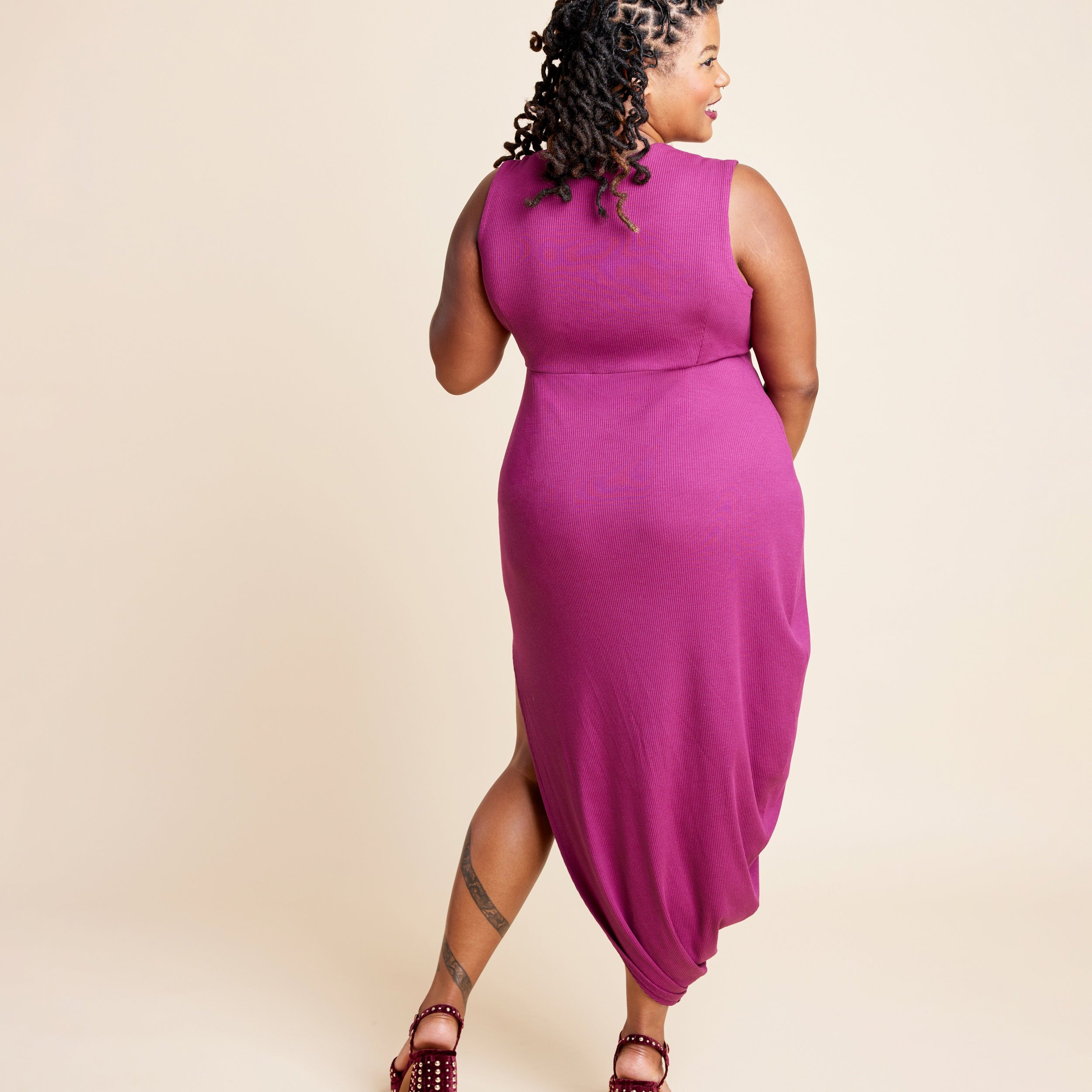 Woman wearing a magenta sleeveless dress on a beige background. This is the Grafton Dress, Top & Skirt sewing pattern from Cashmerette.