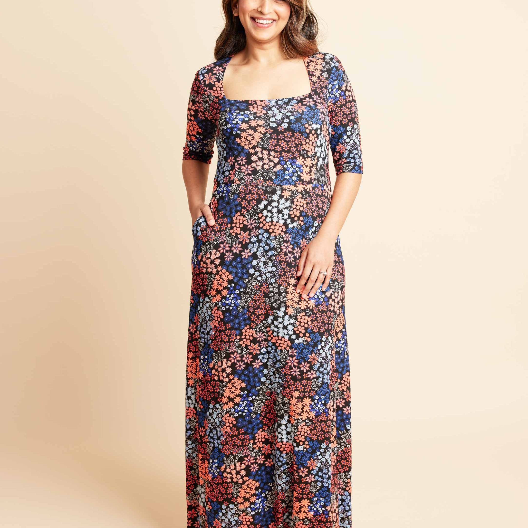 Woman wearing a floral dress on a beige background. This is the Grafton Dress, Top & Skirt sewing pattern from Cashmrette.
