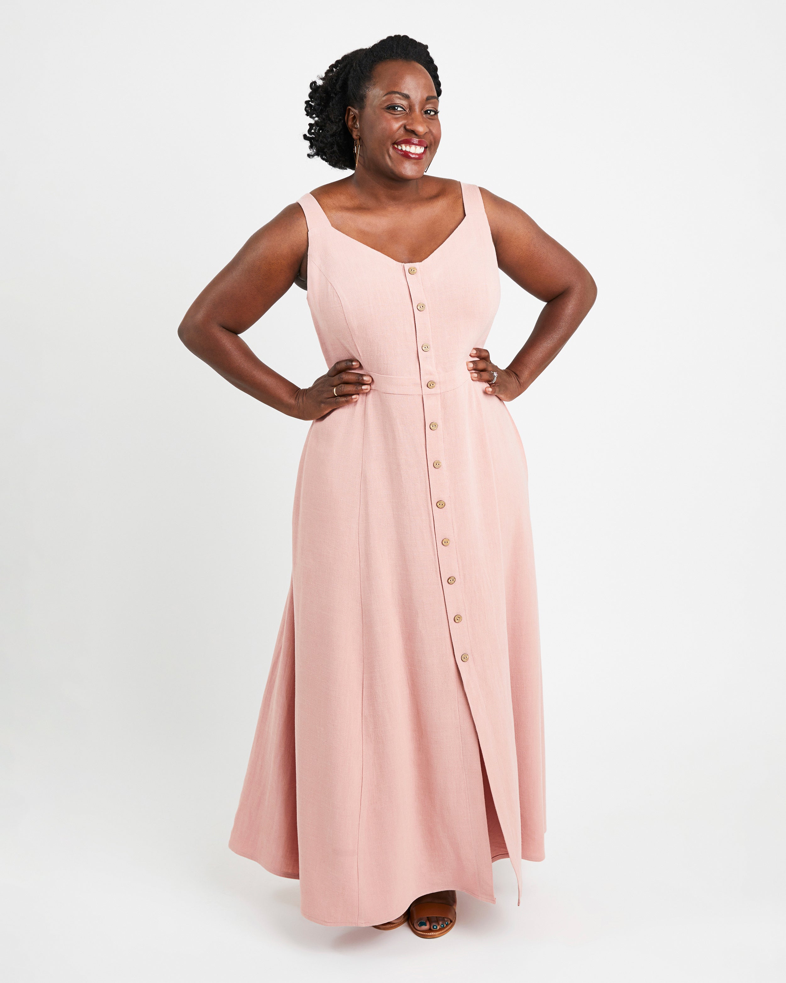 Woman wearing a pink sleeveless dress with buttons on a white background. This is the Holyoke Maxi Dress & Skirt sewing pattern from Cashmerette.