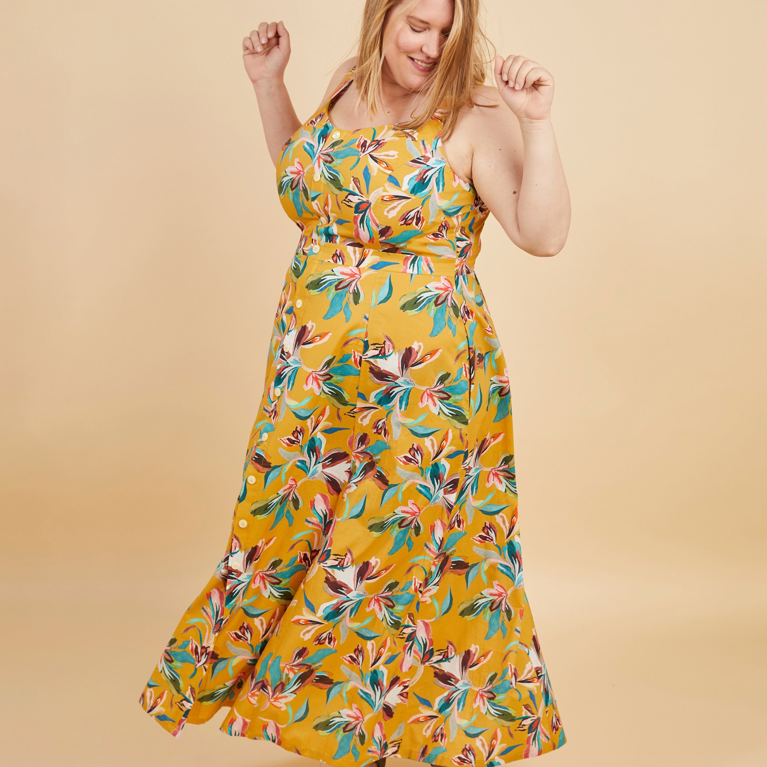 Woman wearing a yellow floral dress against a beige background. This is the Holyoke Maxi Dress & Skirt sewing pattern from Cashmerette.