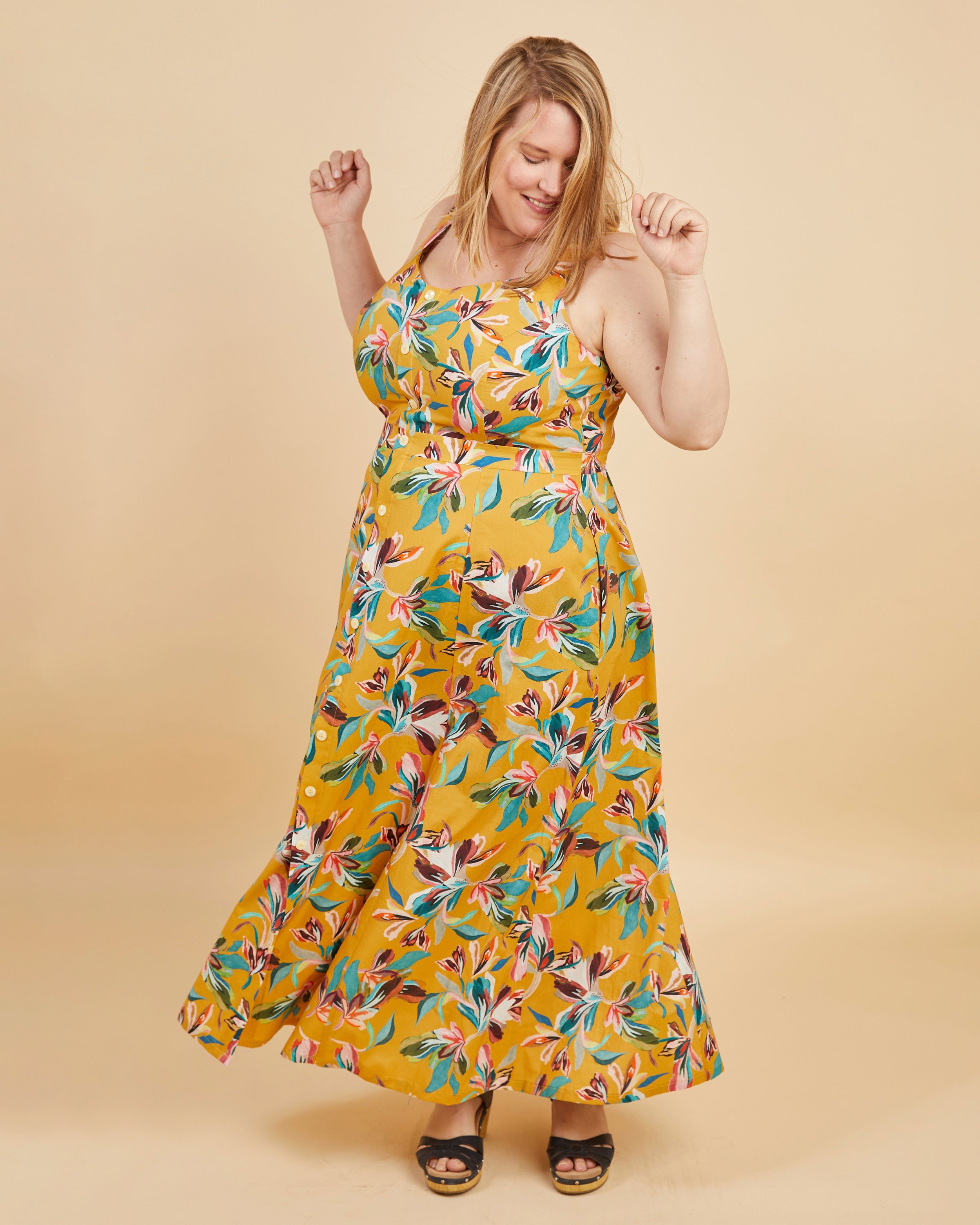 Woman wearing a yellow floral dress against a beige background. This is the Holyoke Maxi Dress & Skirt sewing pattern from Cashmerette.