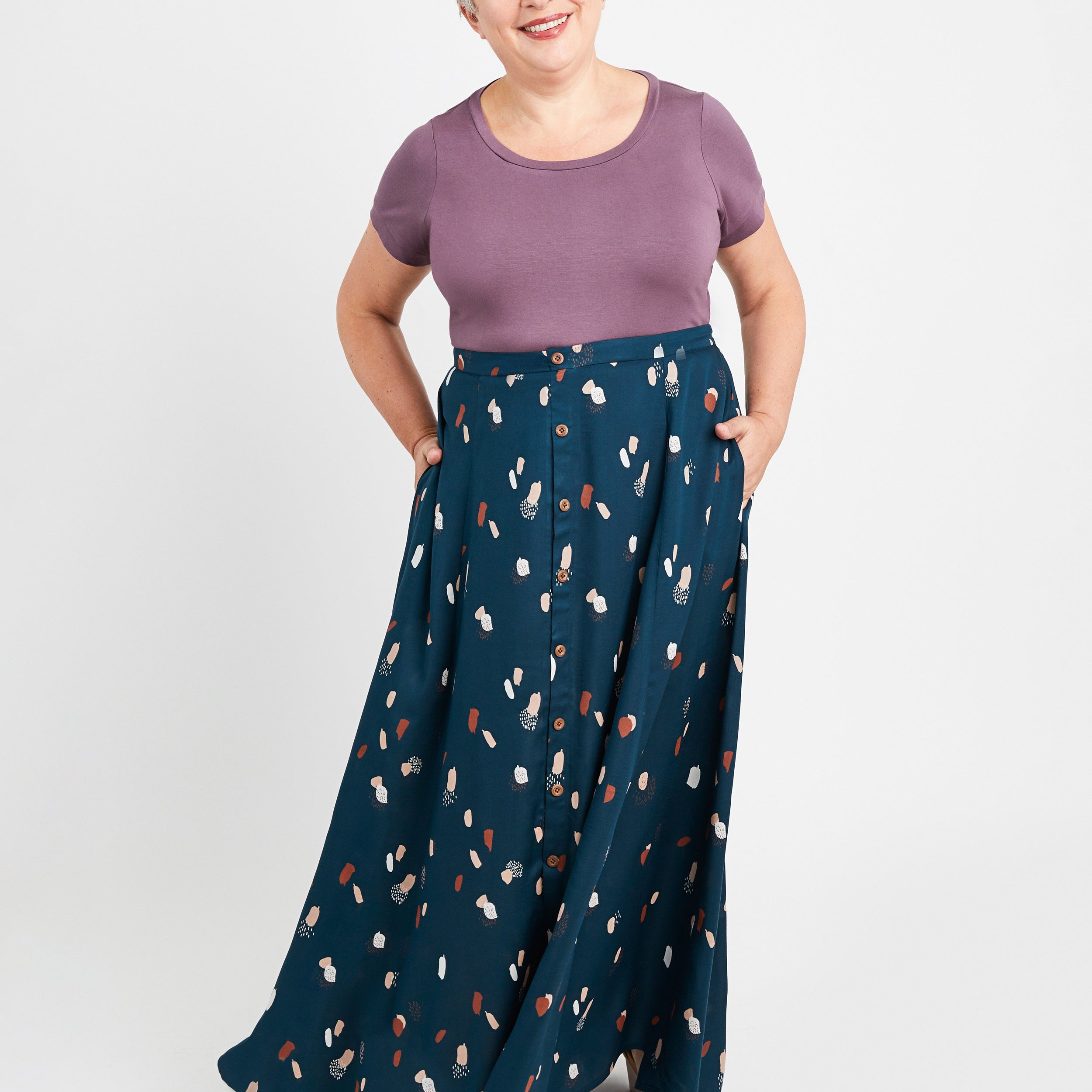 Woman wearing a purple top and navy patterned pants on a white background. This is the Holyoke Maxi Dress & Skirt sewing pattern from Cashmerette.