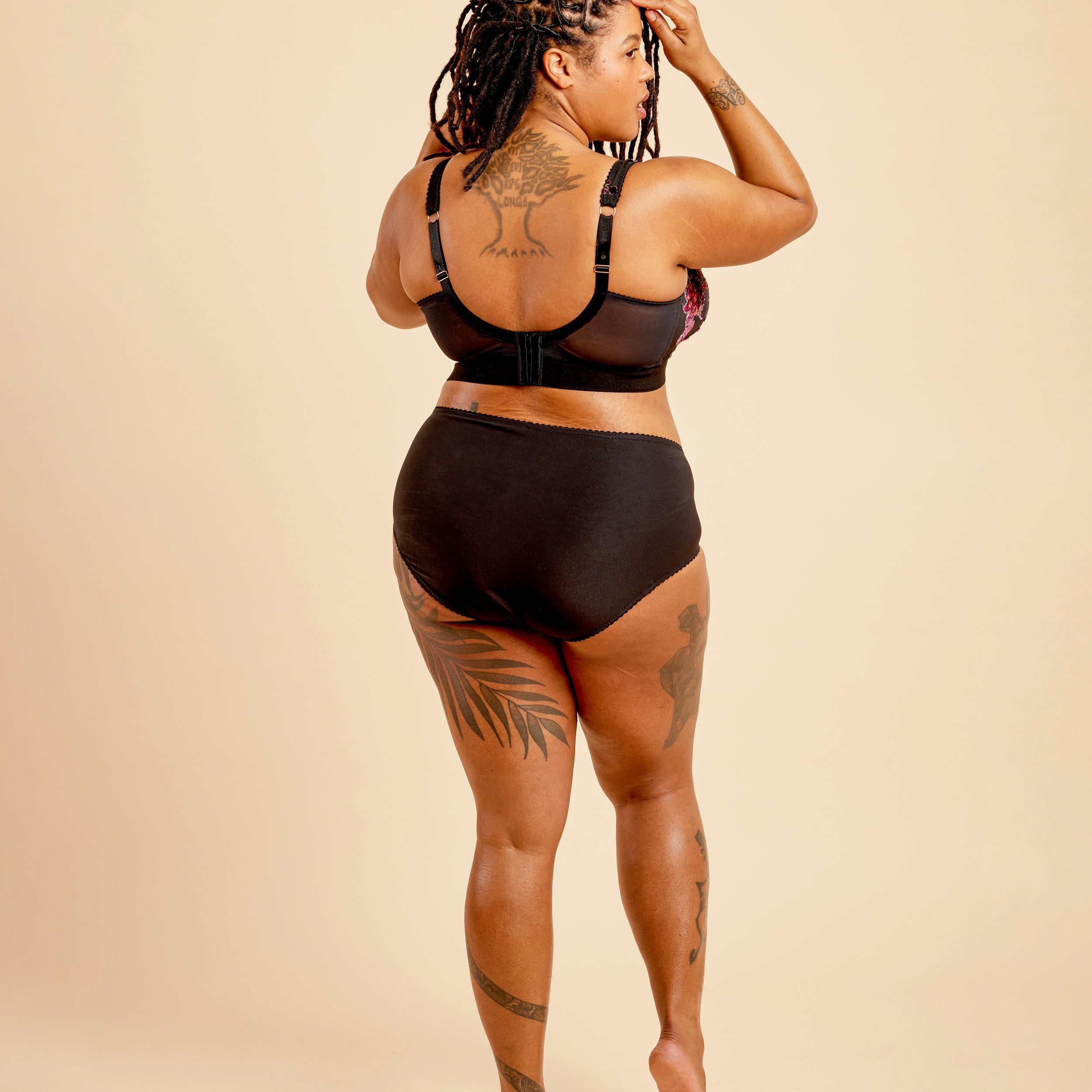 Person wearing a black bikini set on a beige background. This bralette is the Loftus Bralette sewing pattern from Cashmerette.