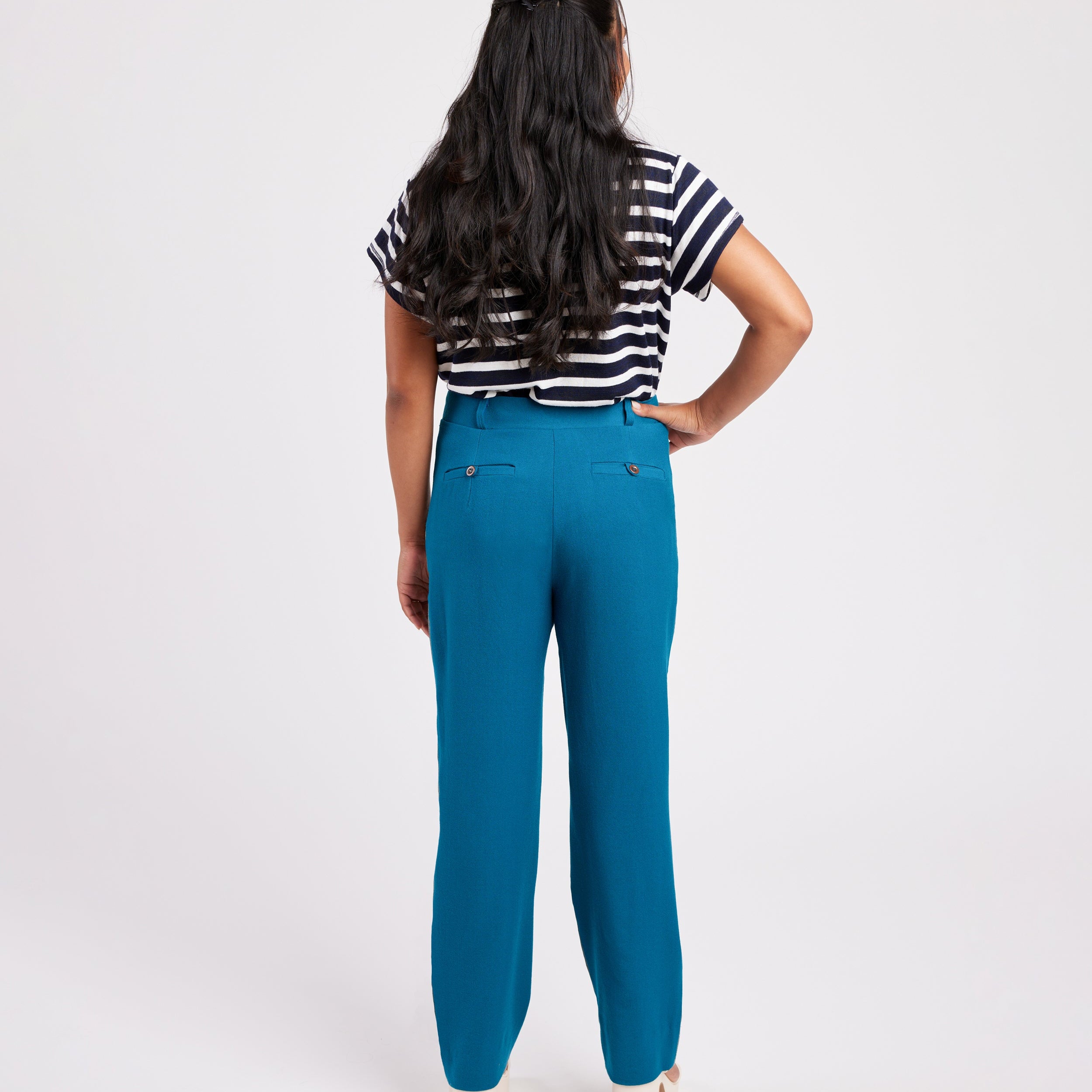 Person wearing blue pants and a striped shirt on a white background. These pants are the Meriam Trousers sewing pattern from Cashmerette.