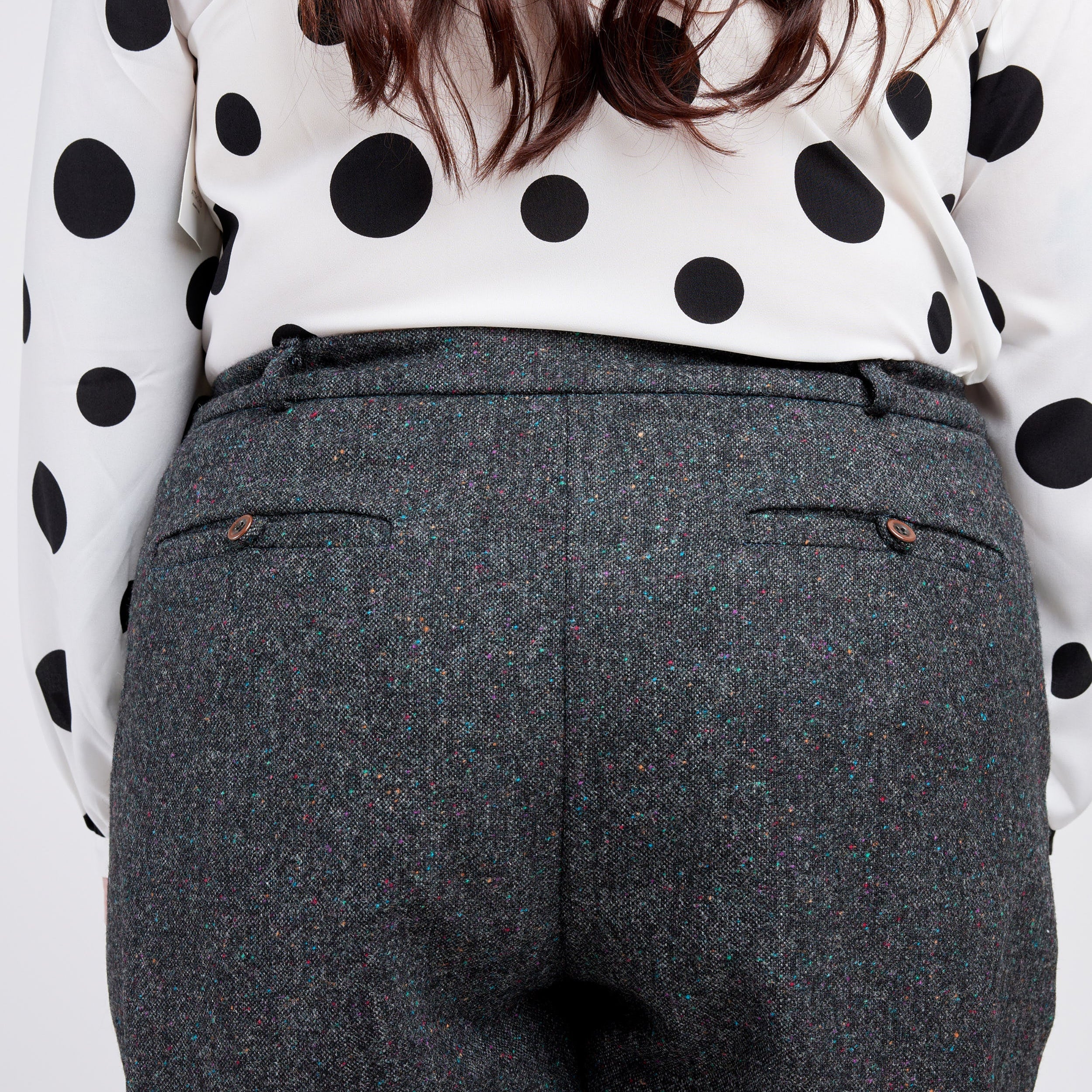 Person wearing a polka dot blouse and gray pants on a white background. These pants are the Meriam Trousers sewing pattern from Cashmerette.