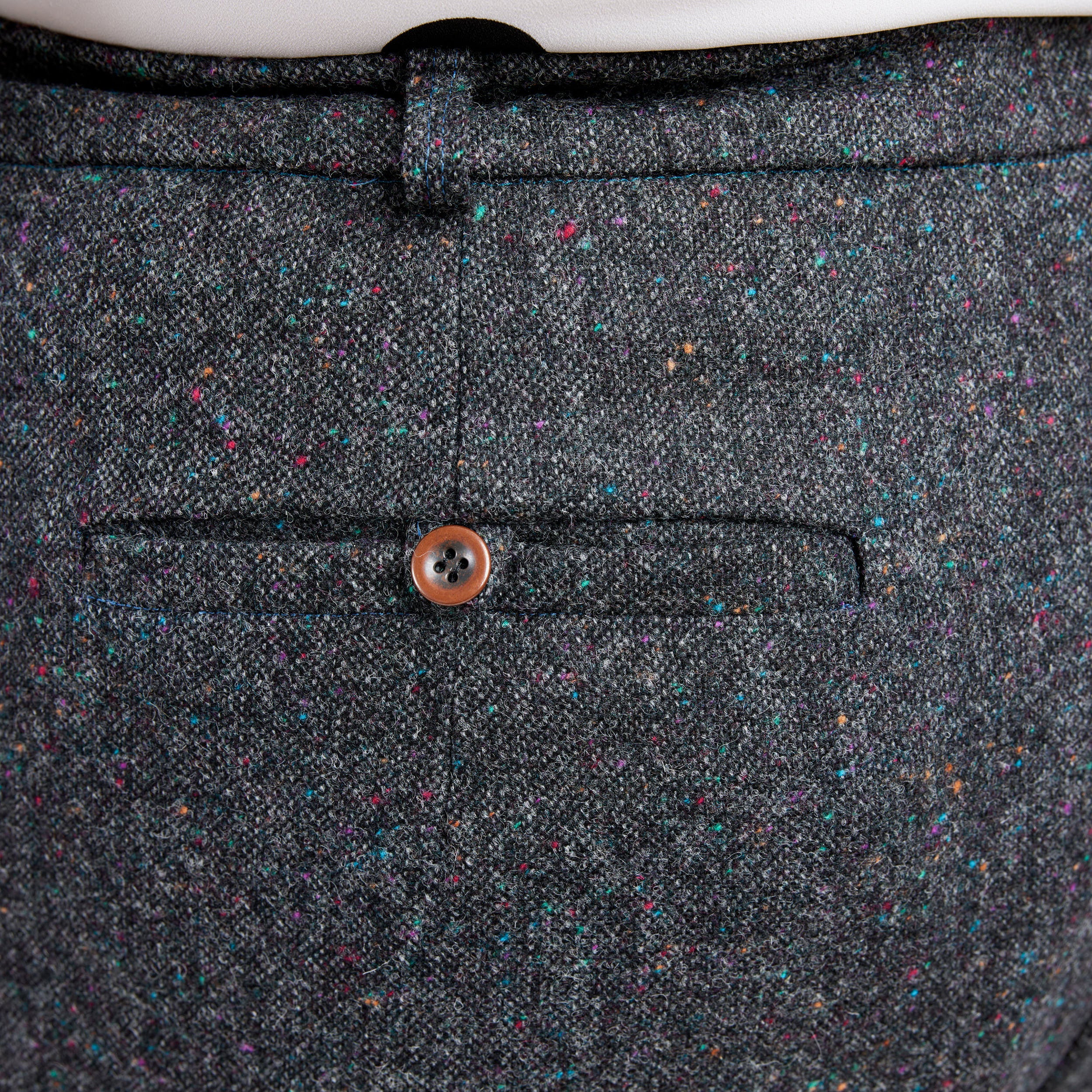 Close-up of a gray textured fabric with a button on a white background. These pants are the Meriam Trousers sewing pattern from Cashmerette.