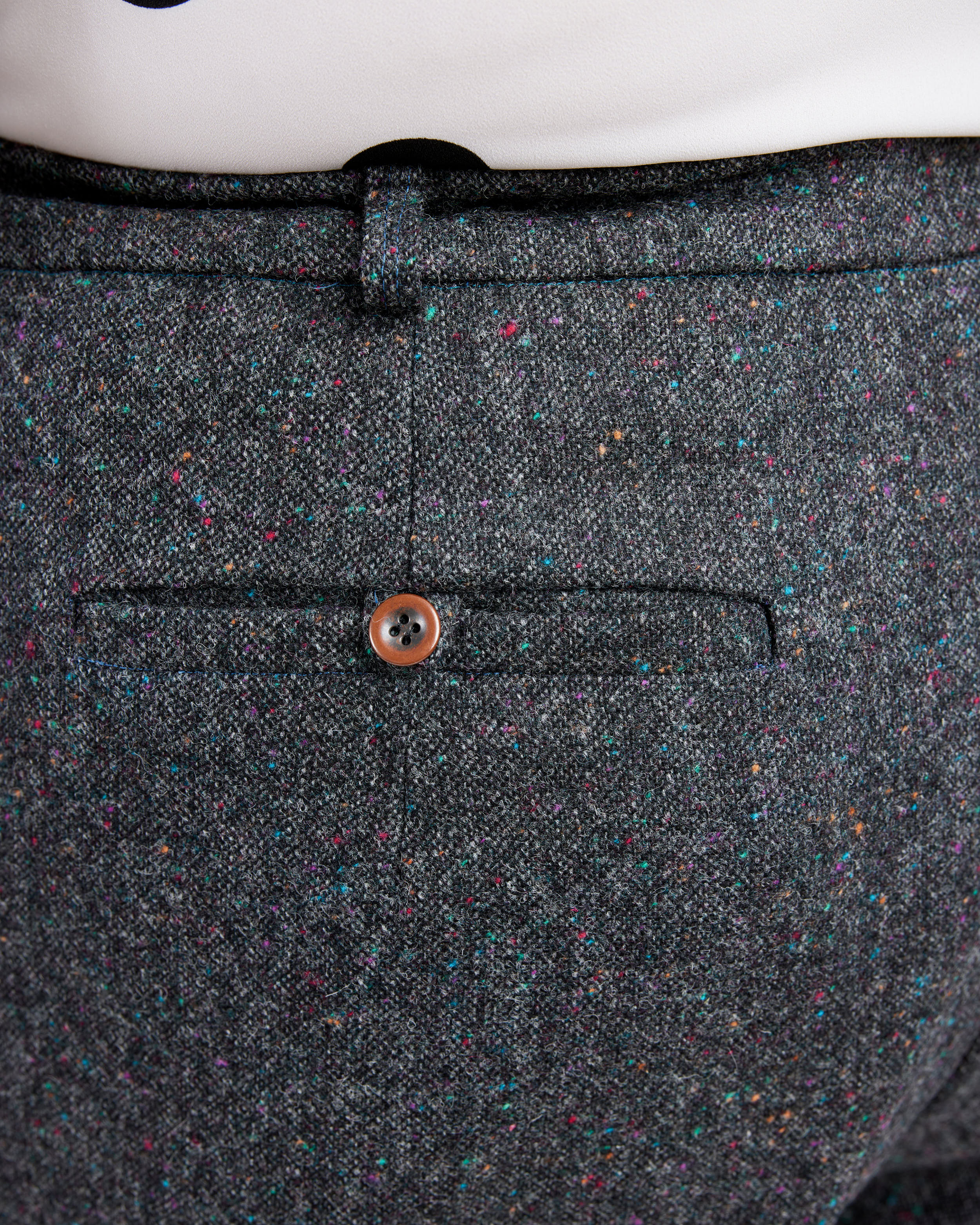 Close-up of a gray textured fabric with a button on a white background. These pants are the Meriam Trousers sewing pattern from Cashmerette.