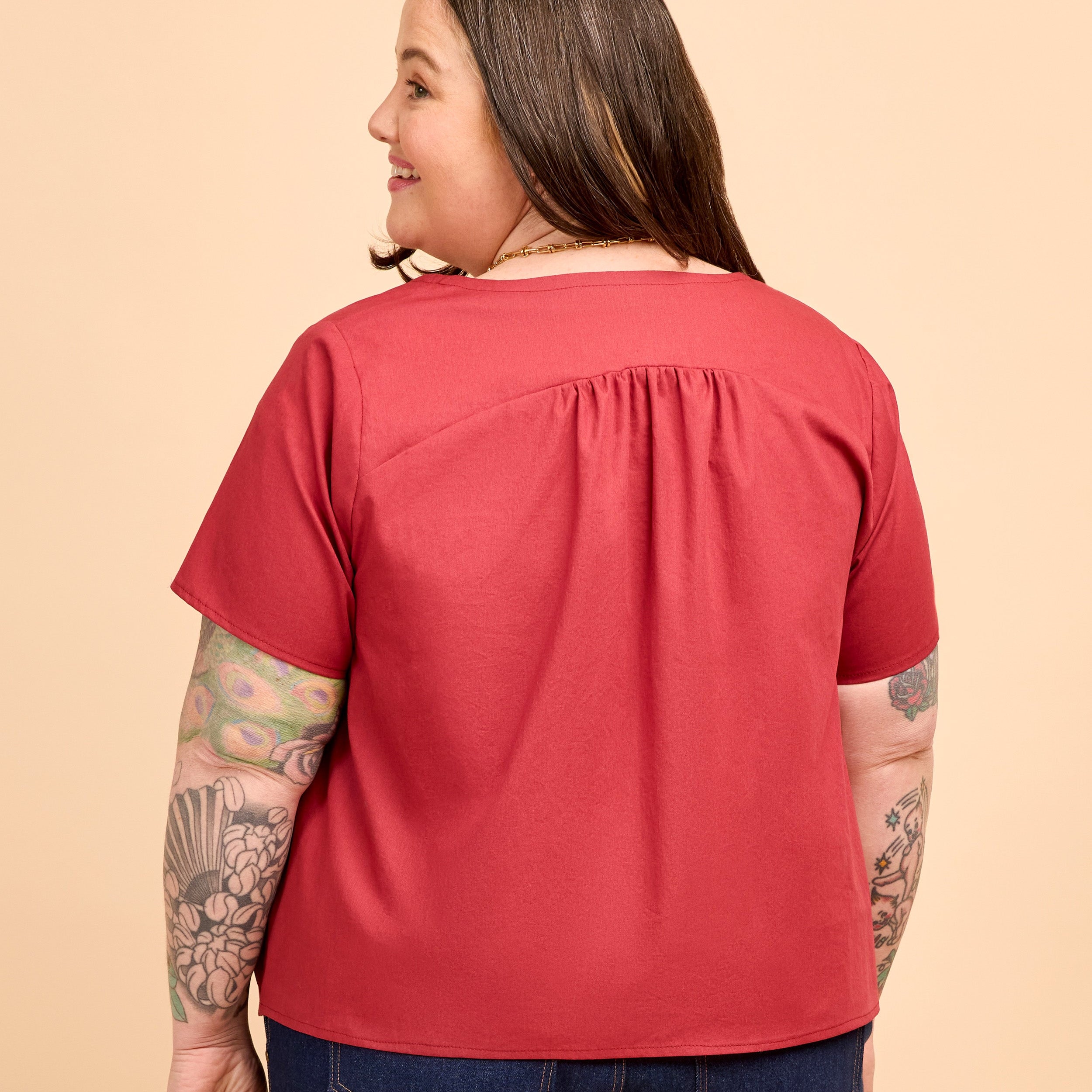 Person wearing a red shirt on a beige background. This is the Montrose Top sewing pattern from Cashmerette.