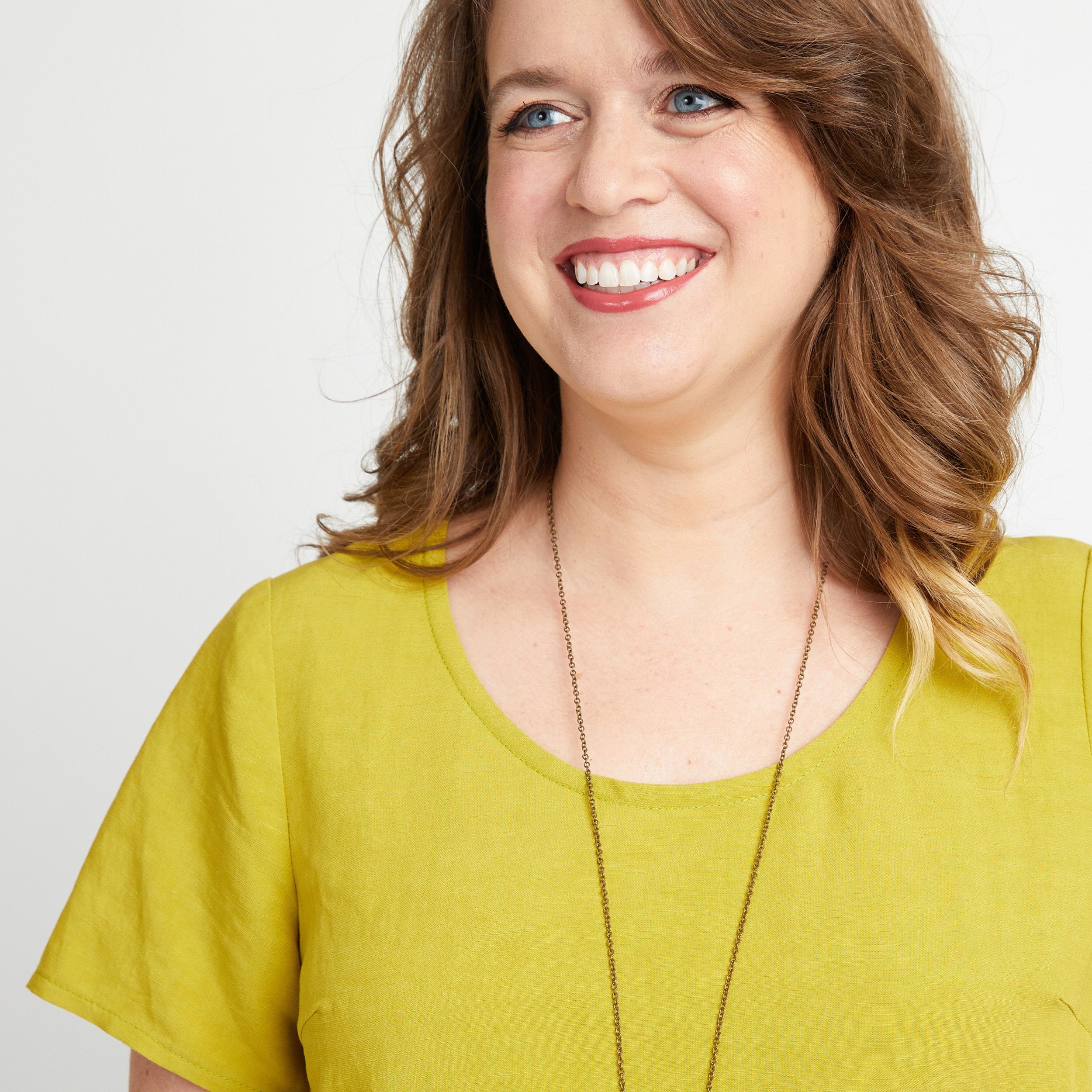 Woman wearing a yellow shirt with a plain background. This top is the Montrose Top sewing pattern from Cashmerette.