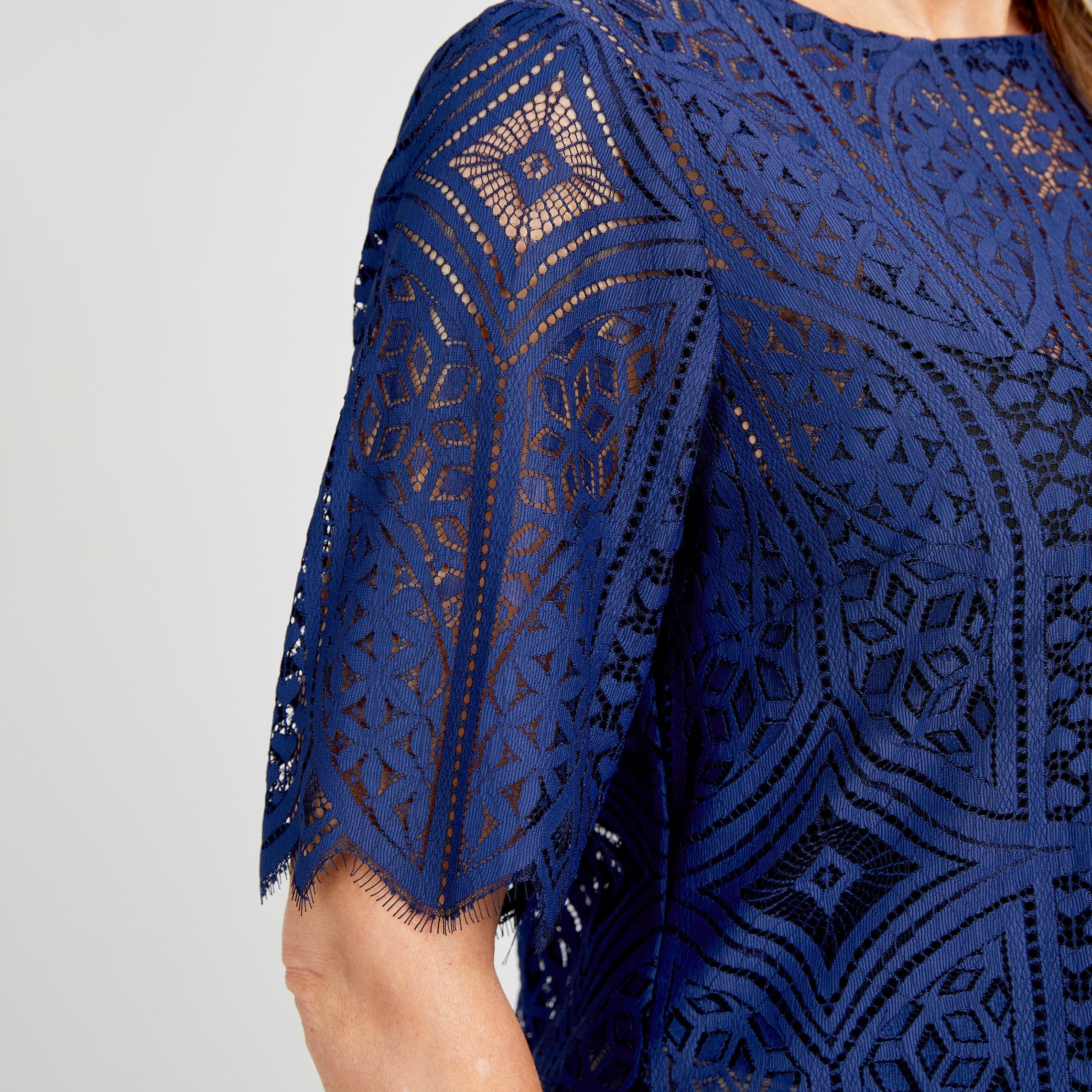 Navy blue lace dress with geometric pattern on a plain background. This top is the Montrose Top sewing pattern from Cashmerette.