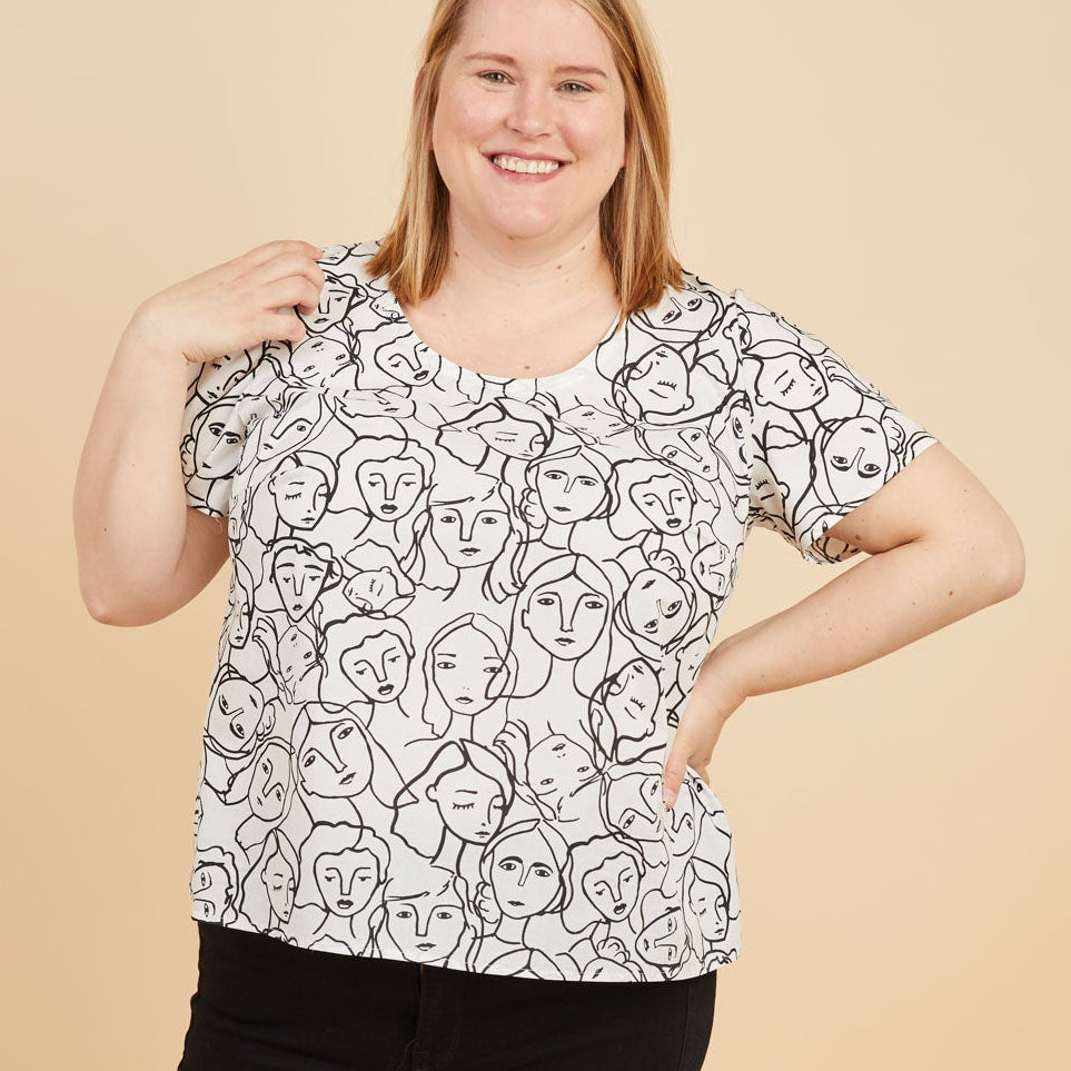 Woman wearing a black and white patterned top and black pants on a beige background. This is the Montrose Top sewing pattern from Cashmerette.