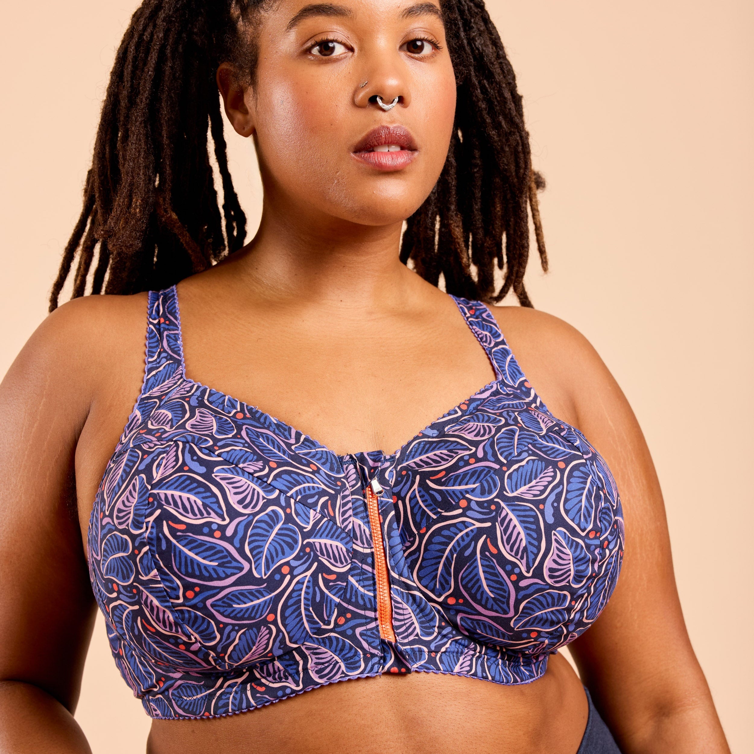 Woman wearing a blue patterned sports bra against a beige background. This is the Cashmerette Somerville Sports Bra sewing pattern for big boobs.