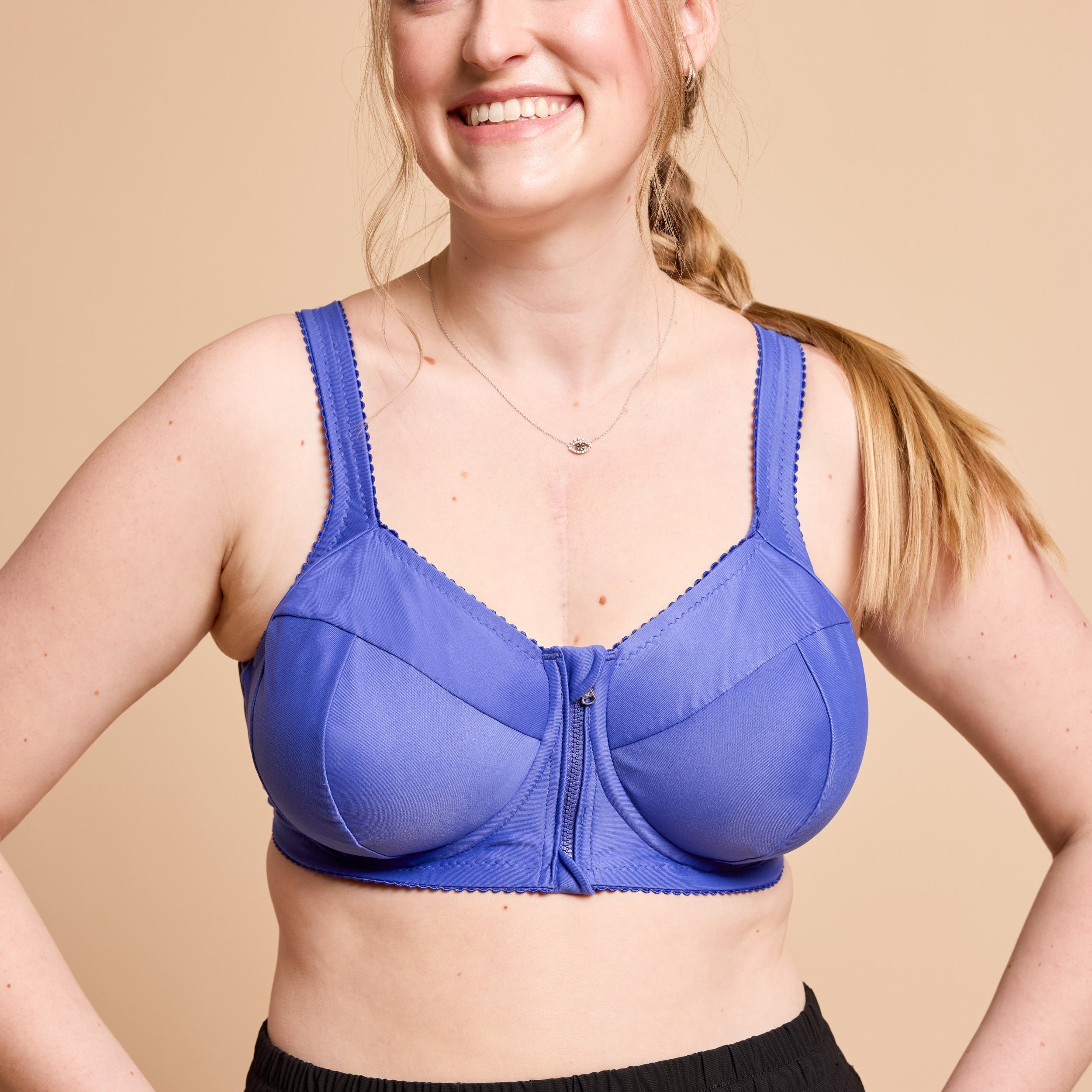 Woman wearing a blue bra against a beige background. This is the Cashmerette Somerville Sports Bra sewing pattern for big boobs.