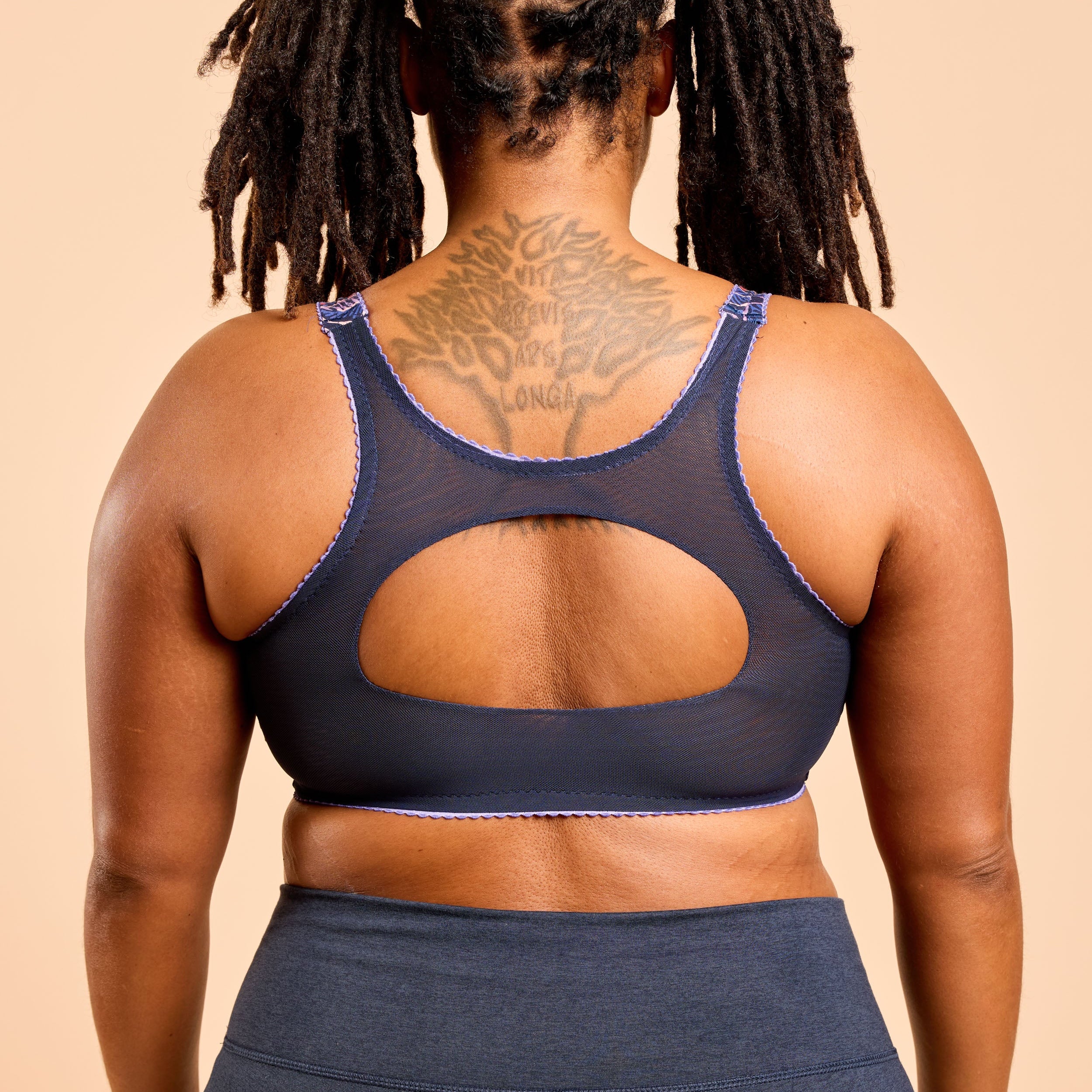 Person wearing a navy blue sports bra and leggings on a beige background. This is the Cashmerette Somerville Sports Bra sewing pattern for big boobs.