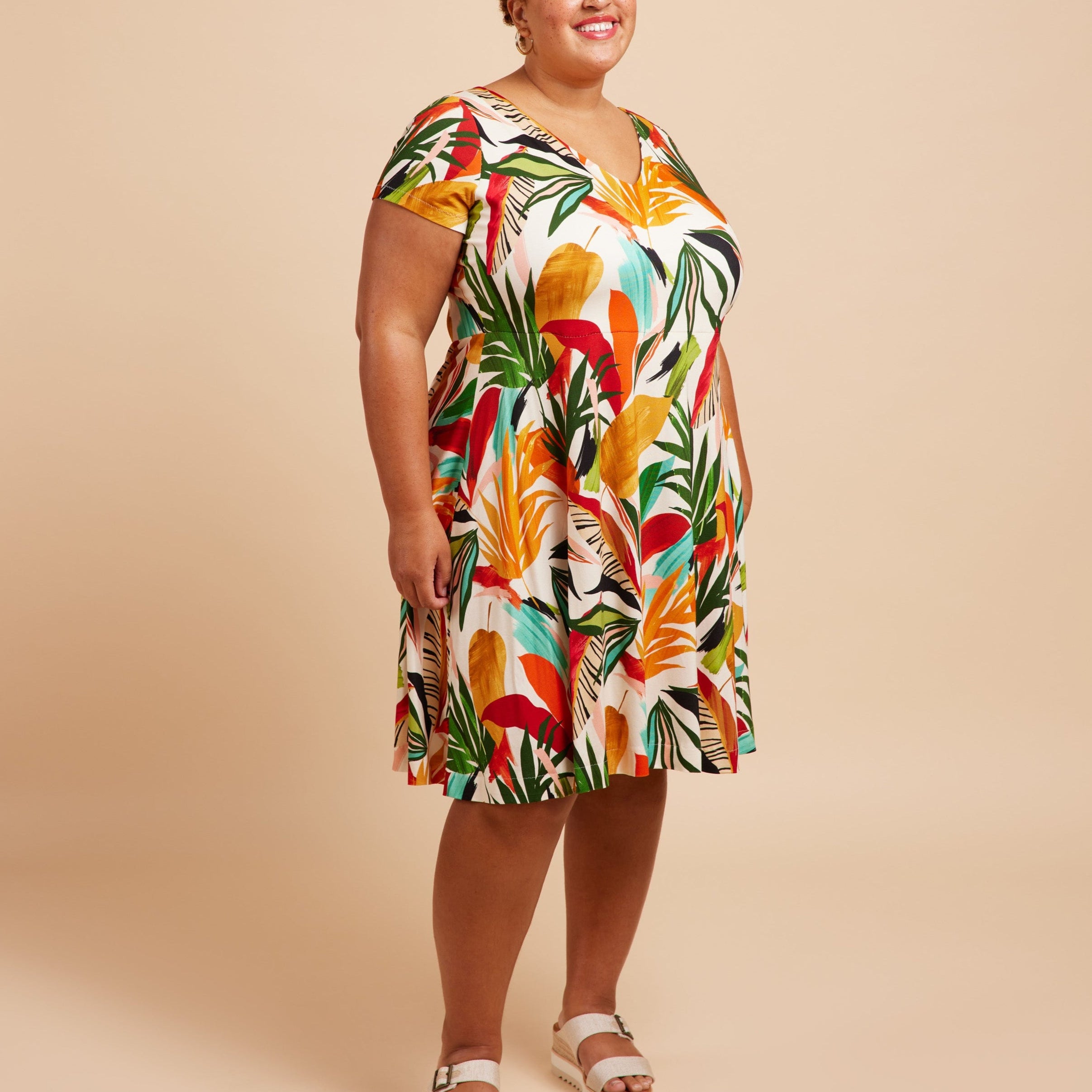 Woman wearing a colorful tropical print dress on a beige background