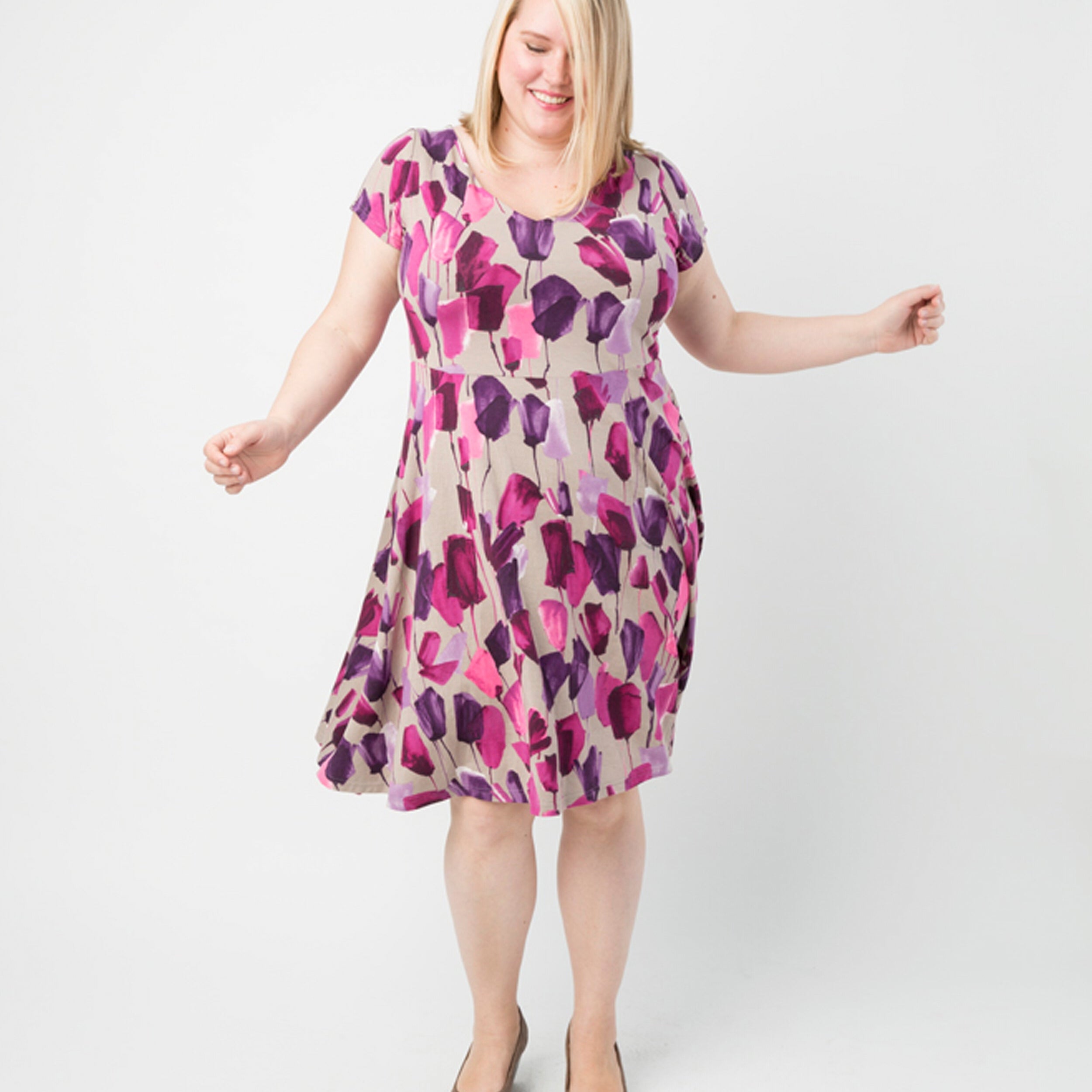 Woman wearing a floral dress on a white background. This dress is the Turner Dress sewing pattern from Cashmerette.