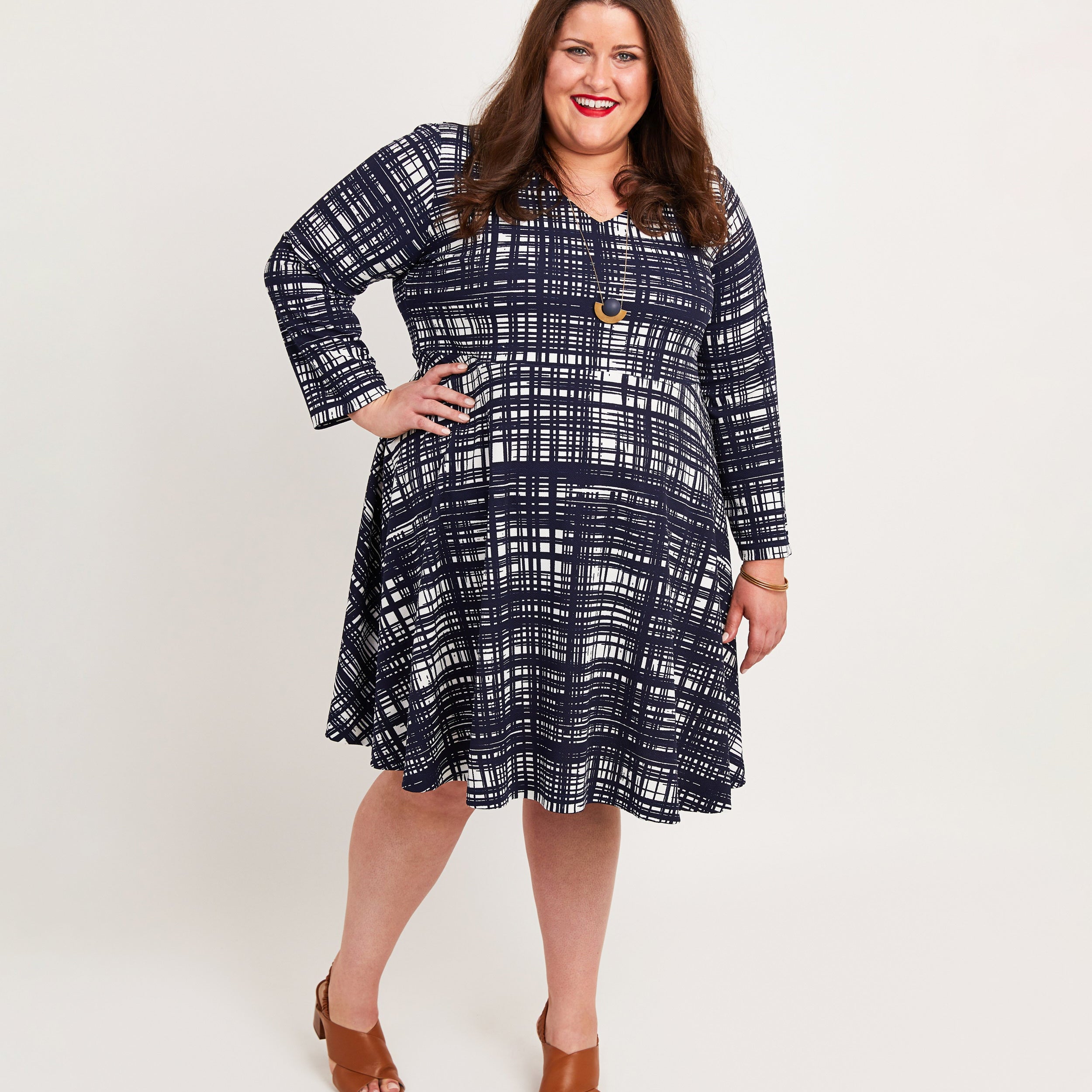 Woman wearing a blue plaid dress on a white background. This dress is the Turner Dress sewing pattern from Cashmerette.