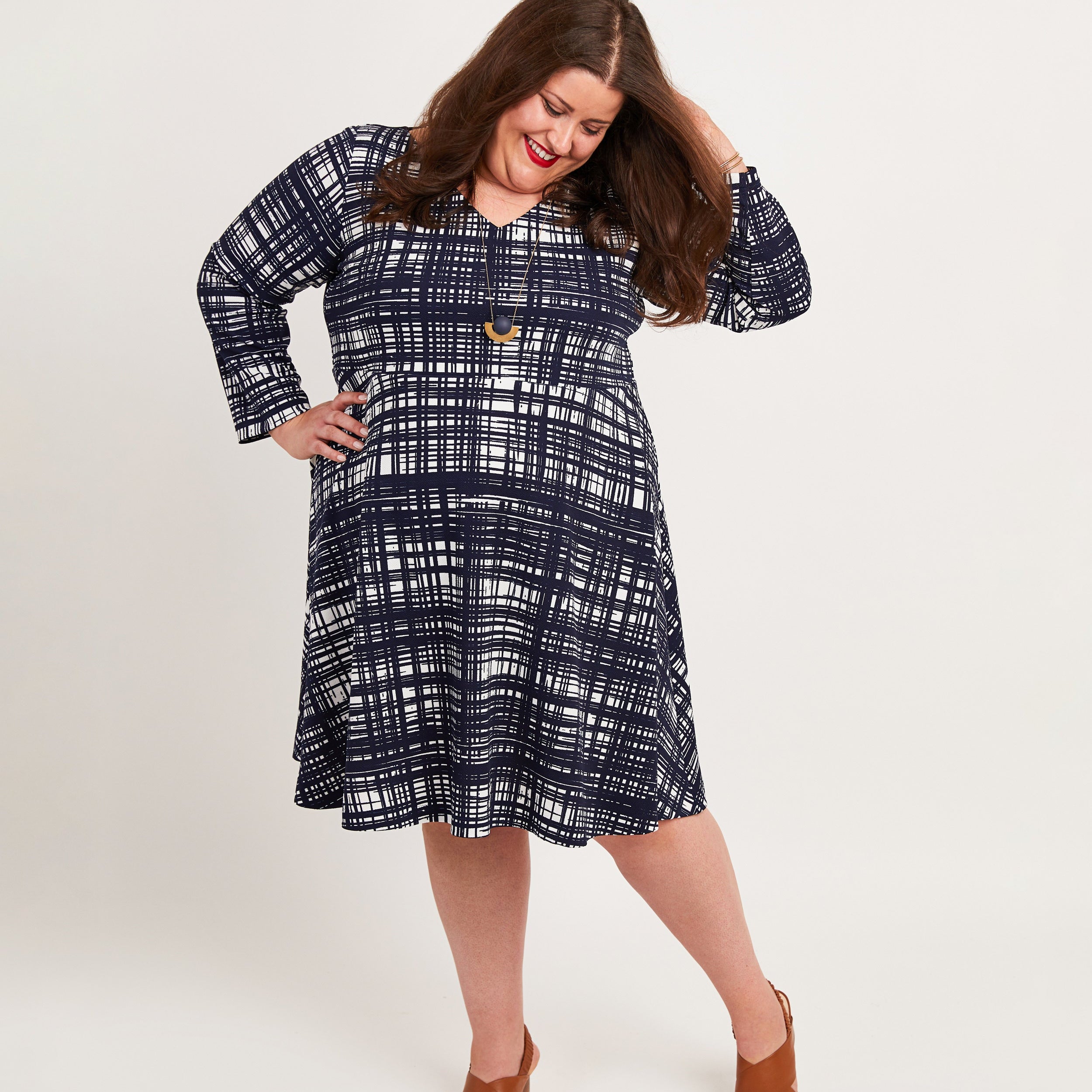 Woman wearing a blue plaid dress on a white background. This dress is the Turner Dress sewing pattern from Cashmerette.