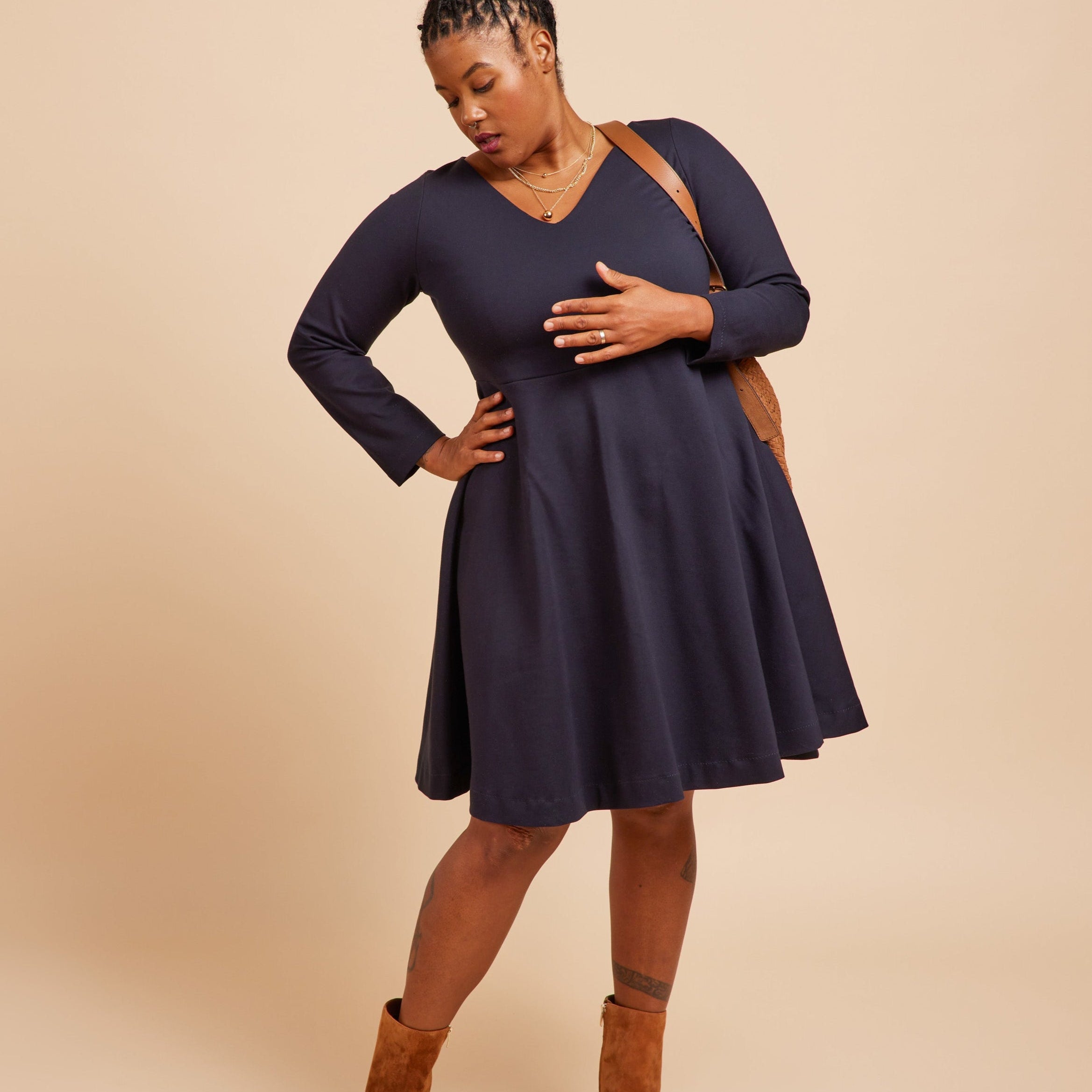 Woman wearing a navy blue dress with long sleeves on a beige background