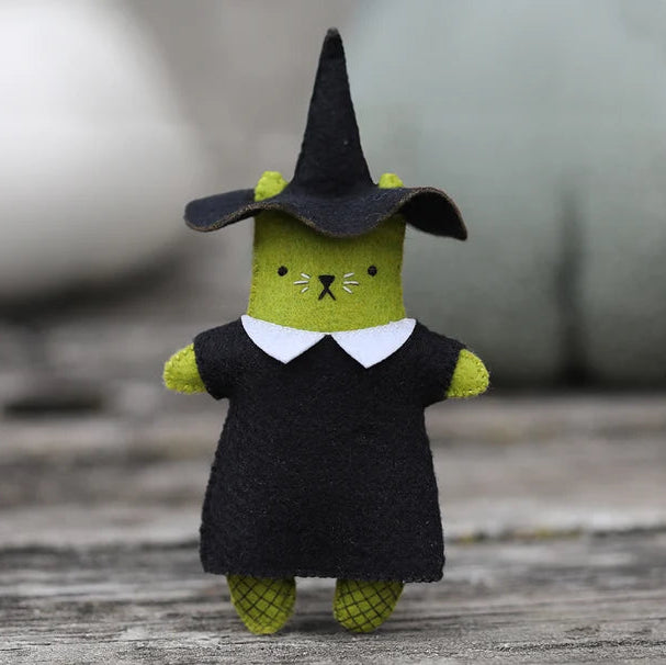 Toy figure of a cat in a witch costume on a wooden surface