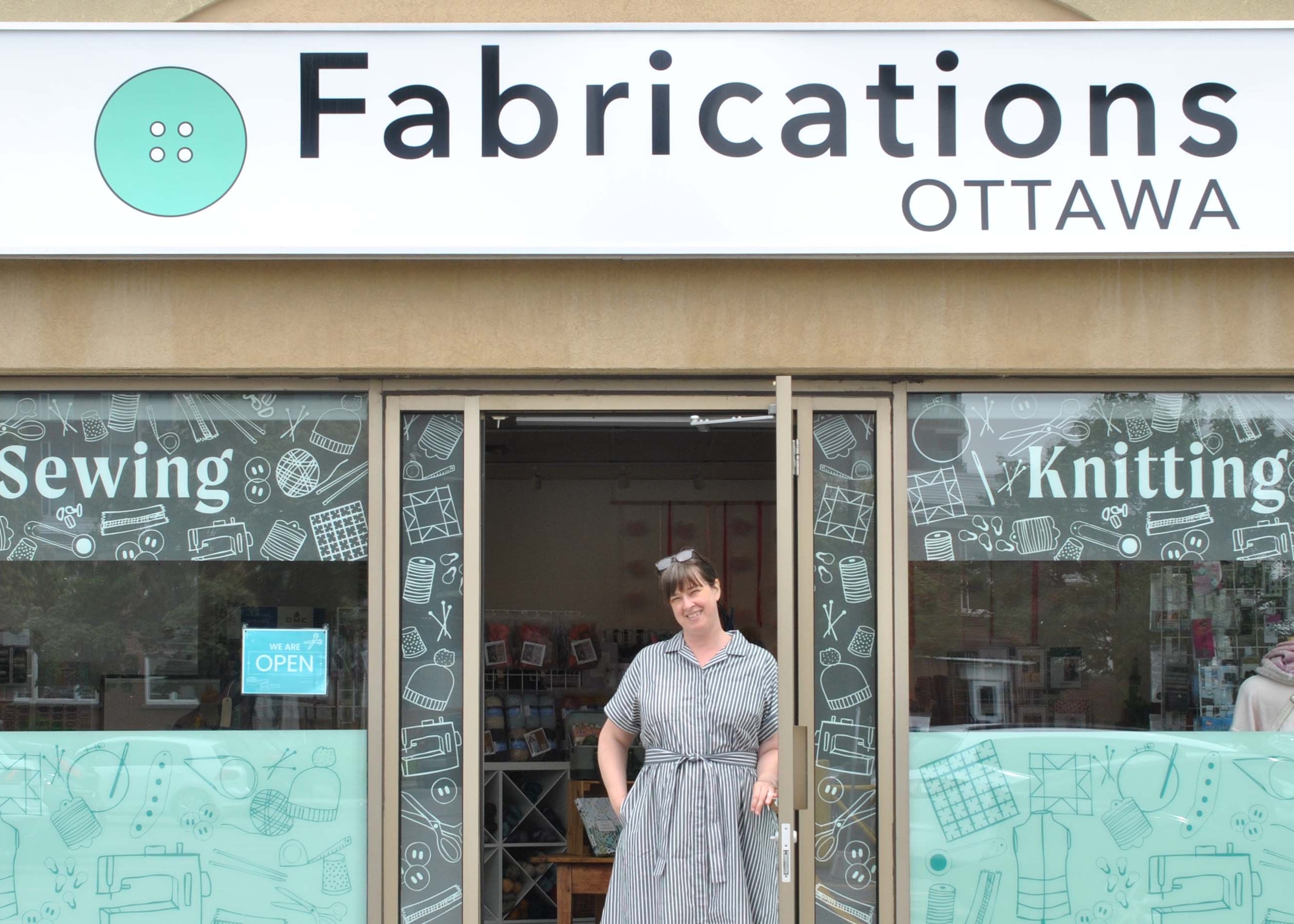 Person standing outside a fabric store named 'Fabrications Ottawa' with 'Sewing' and 'Knitting' displayed on the window.