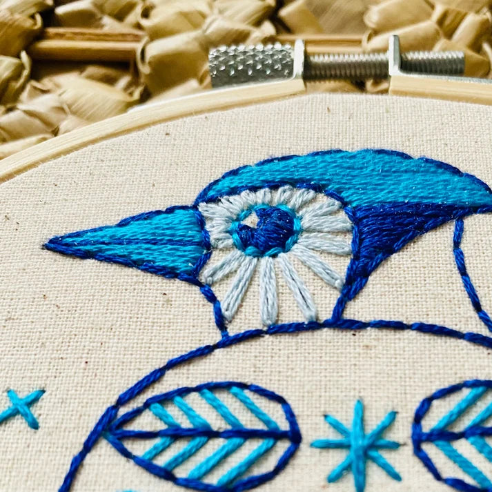 Embroidery hoop with blue jay floral design on beige fabric