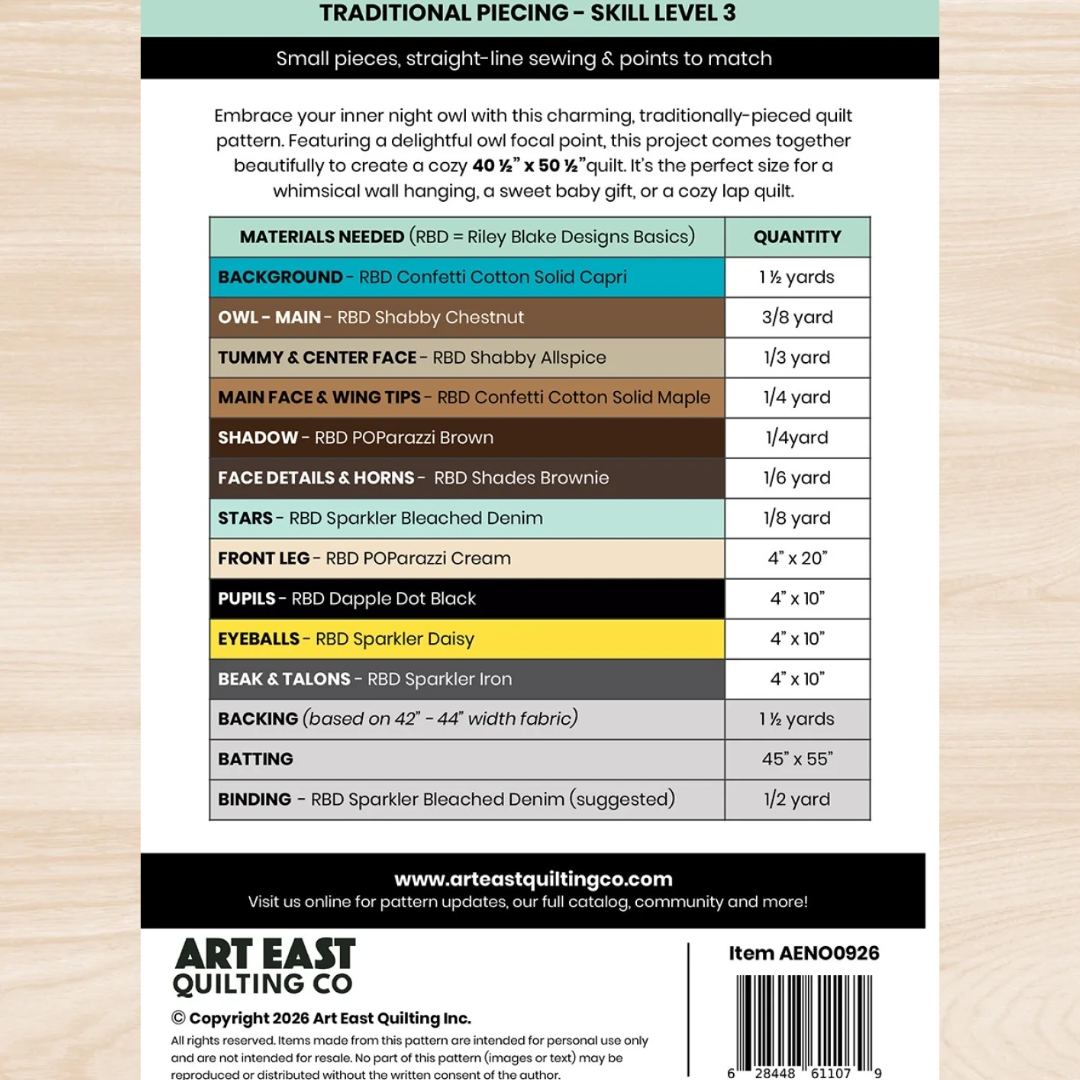 Back of a quilting pattern package for 'Traditional Piecing - Skill Level 3' by Art East Quilting Co., showing a materials list table, product description, website, and barcode on a light wood background.