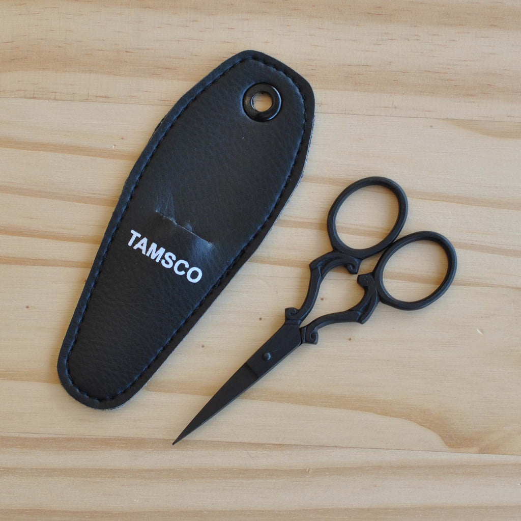 Black embroidery scissors with scroll design on handles.