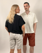 Two people standing side by side wearing casual clothing against a plain background