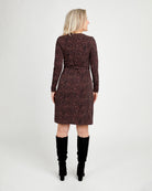 Woman wearing a patterned dress with long sleeves and a belt, standing against a white background.This dress is the Appleton Wrap Dress sewing pattern from Cashmerette.