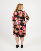 Woman wearing a black floral dress on a white background. This dress is the Appleton Wrap Dress sewing pattern from Cashmerette.
