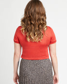 Person wearing a red top and patterned skirt on a plain background. This t-shirt is the Concord T-Shirt sewing pattern from Cashmerette.